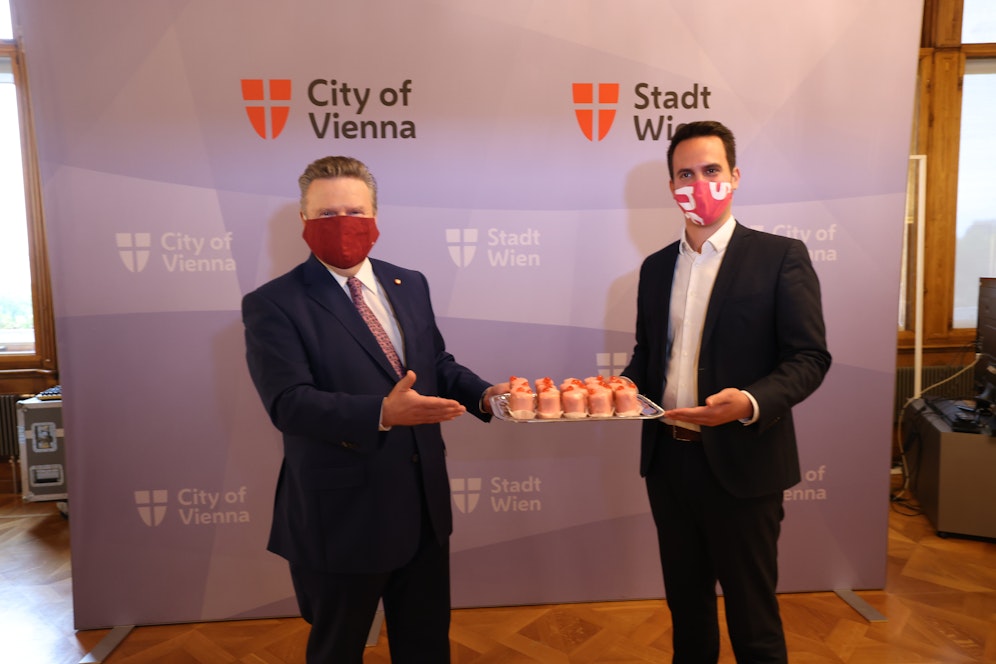 SPÖ-Chef Michael Ludwig serviert Neos-Obmann Christoph Wiederkehr Punschkrapfen