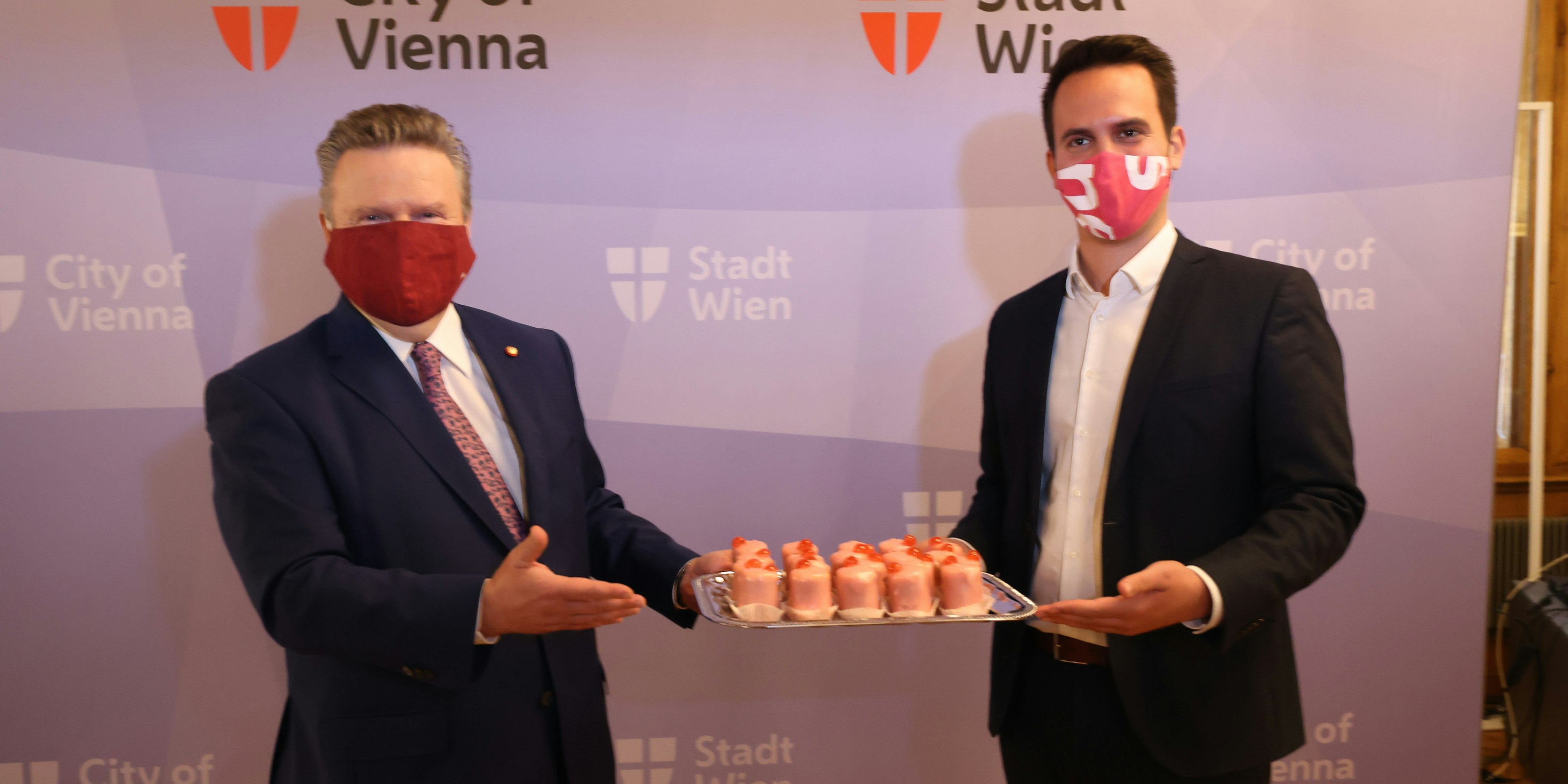 SPÖ-Chef Michael Ludwig serviert Neos-Obmann Christoph Wiederkehr Punschkrapfen