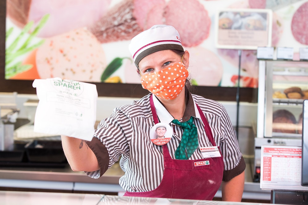 Eine Spar-Mitarbeiterin überreicht einen Feinkost-Einkauf