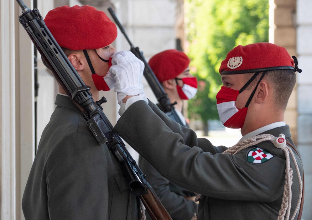 Ein Offizier hilft bei der Adjustierung samt Maske der Garde vor dem Weiheraum im Äußeren Burgtor