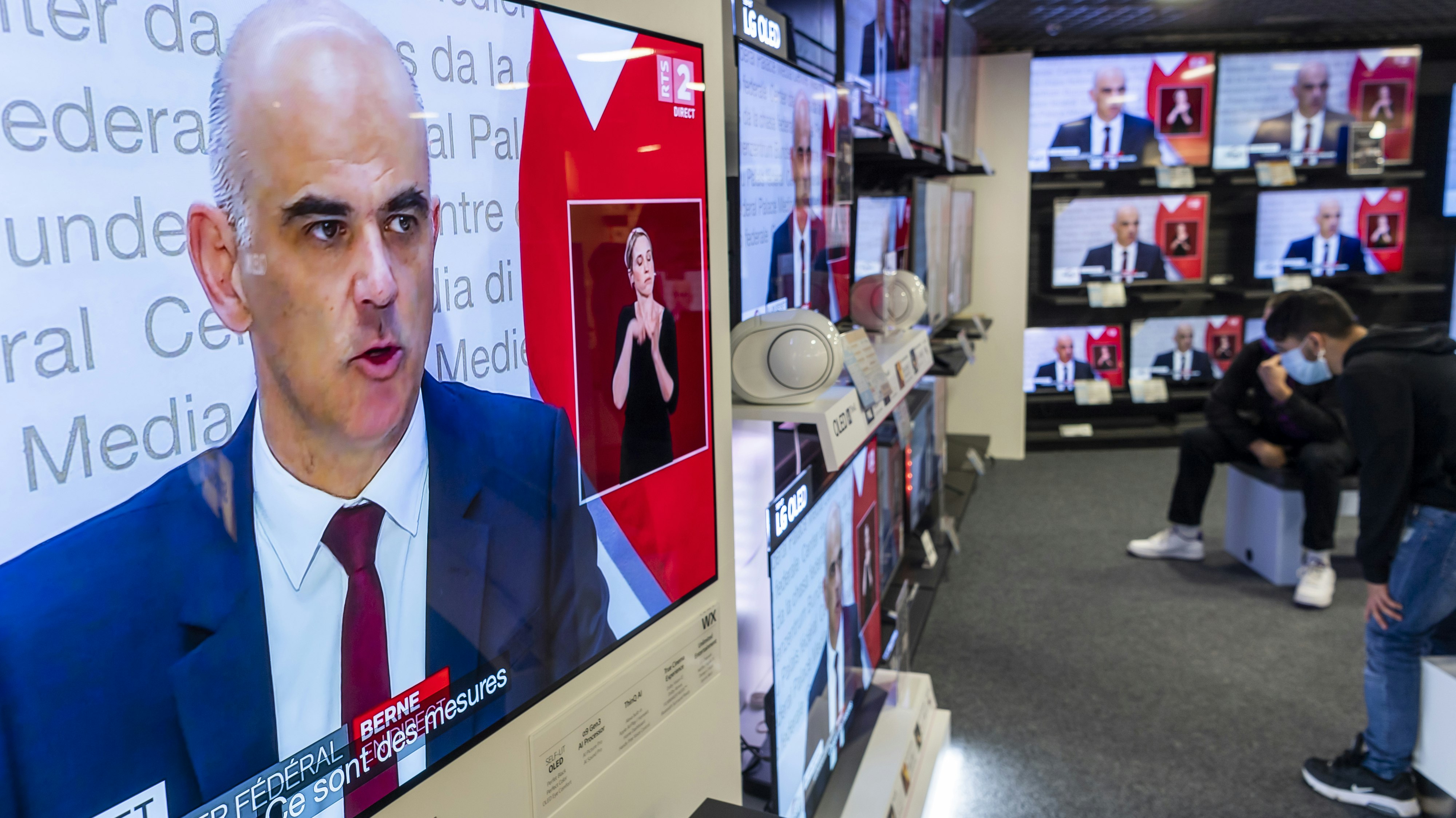 Menschen in Schutzmasken lauschen der Pressekonferenz von Gesundheitsminister Alain Berset: die Schweiz verschärft ihre Coronamaßnahmen