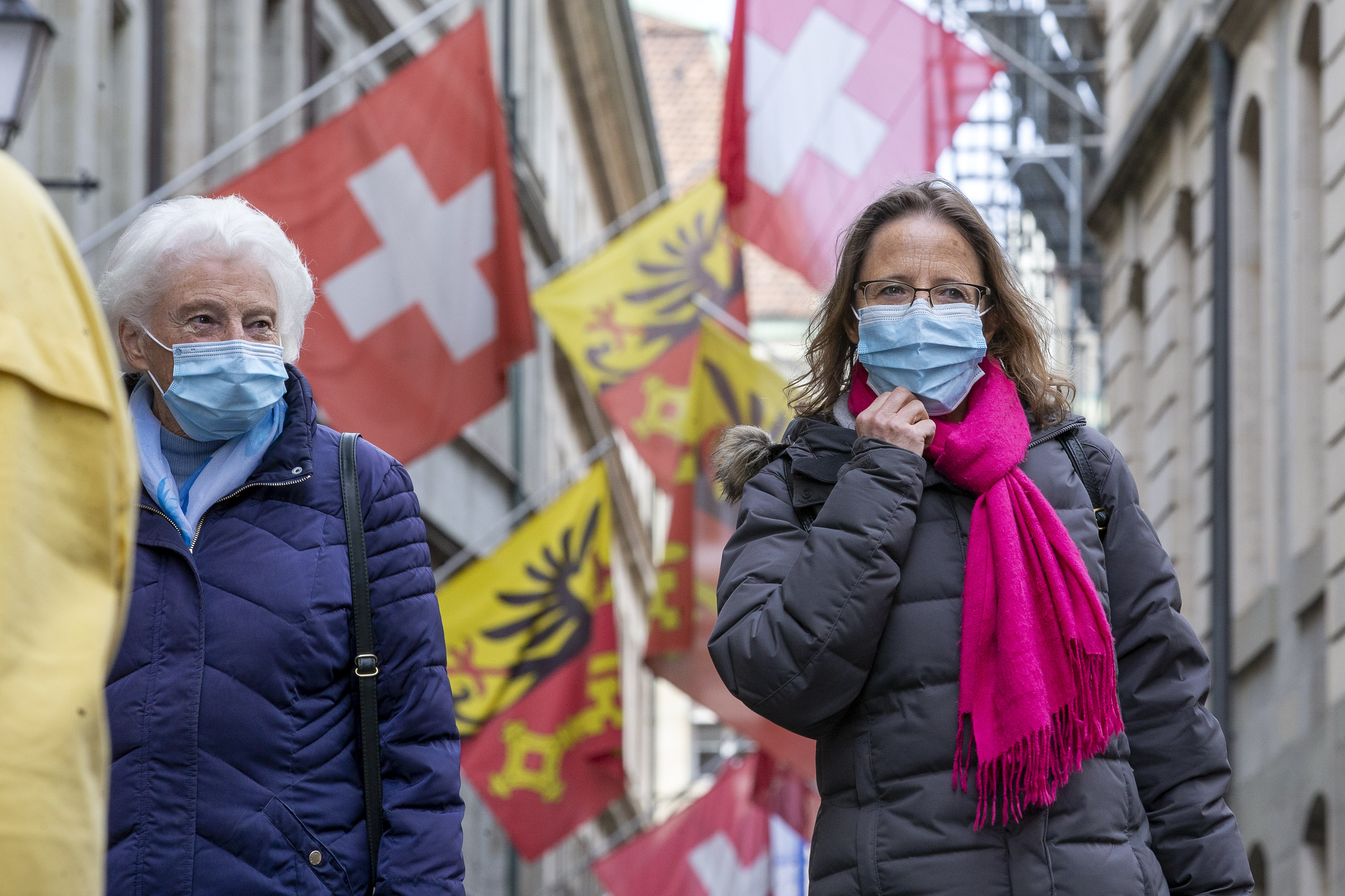 Menschen mit Schutzmasken auf einer Straße in Genf, Schweiz