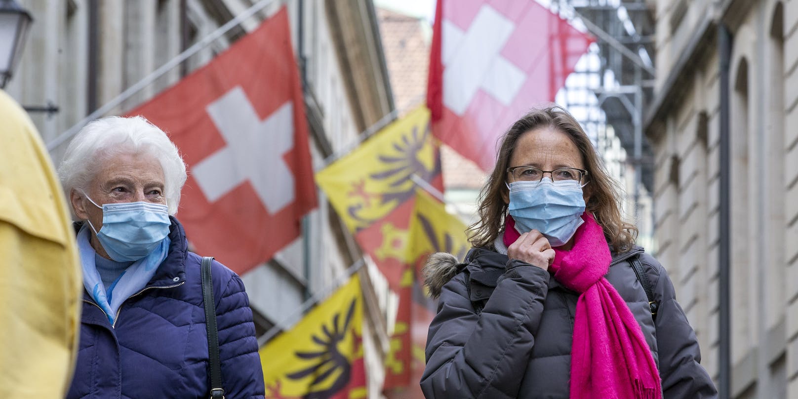 Menschen mit Schutzmasken auf einer Straße in Genf, Schweiz