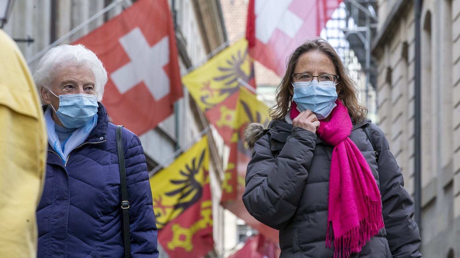 Menschen mit Schutzmasken auf einer Straße in Genf, Schweiz