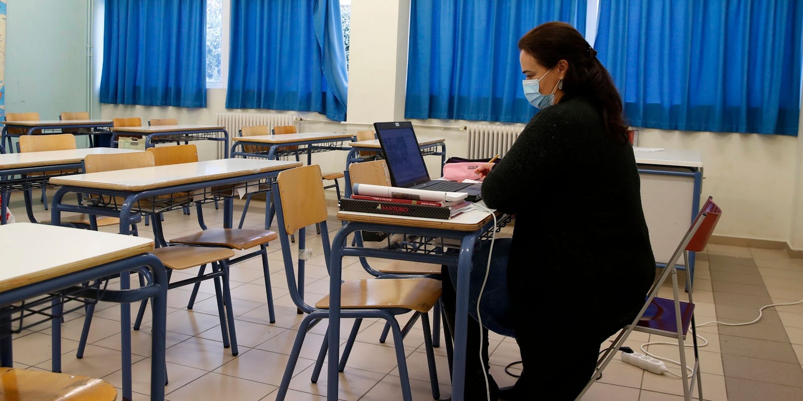 Eine Lehrerin in einem leeren Klassenzimmer. Der Unterricht erfolgt über das Internet. Symbolbild