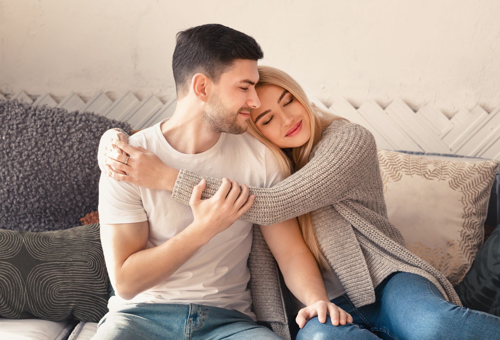 Young man and woman embracing on sofa in living room