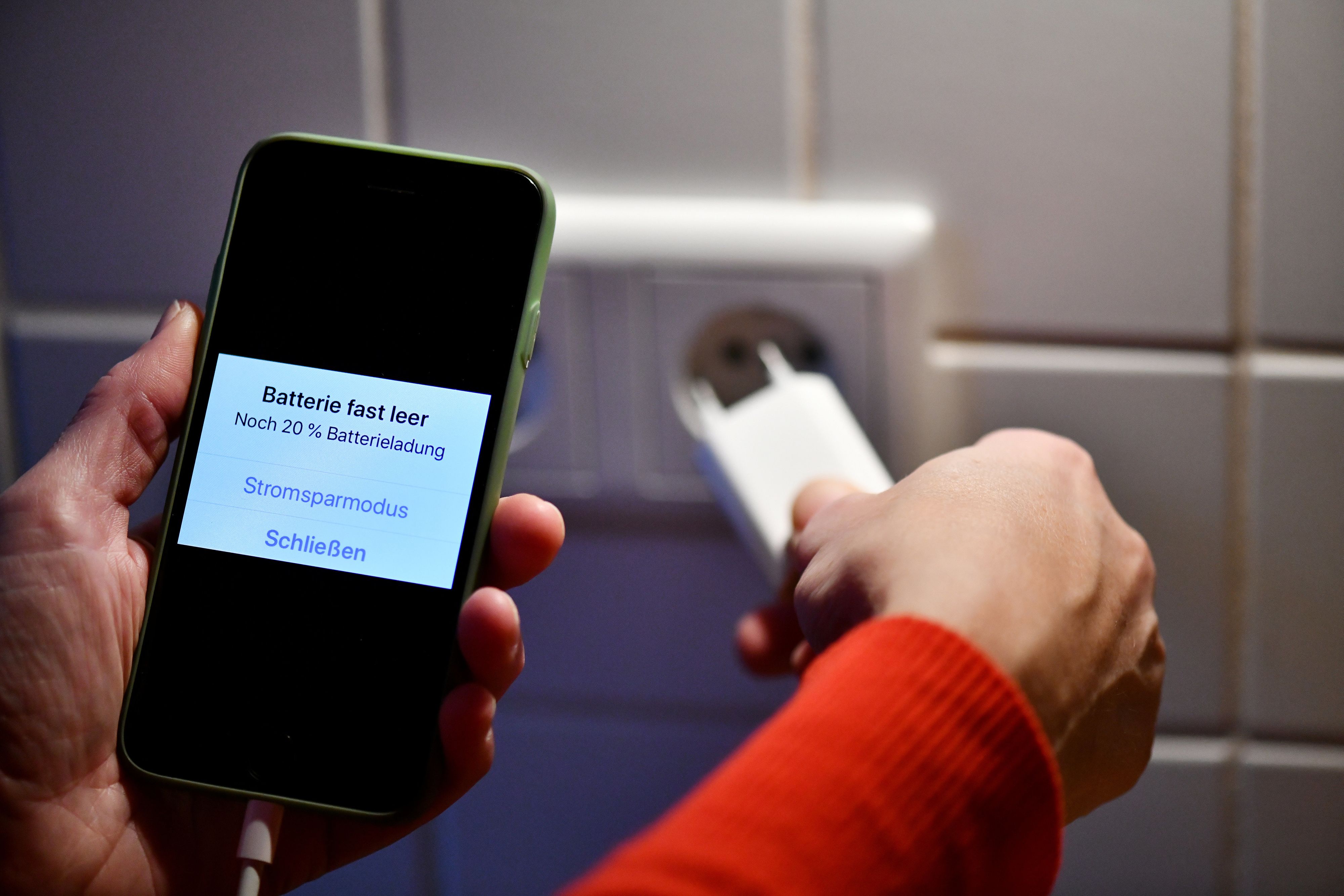 Ein Smartphone-Ladegerät wird in eine Steckdose gesteckt. Symbolbild