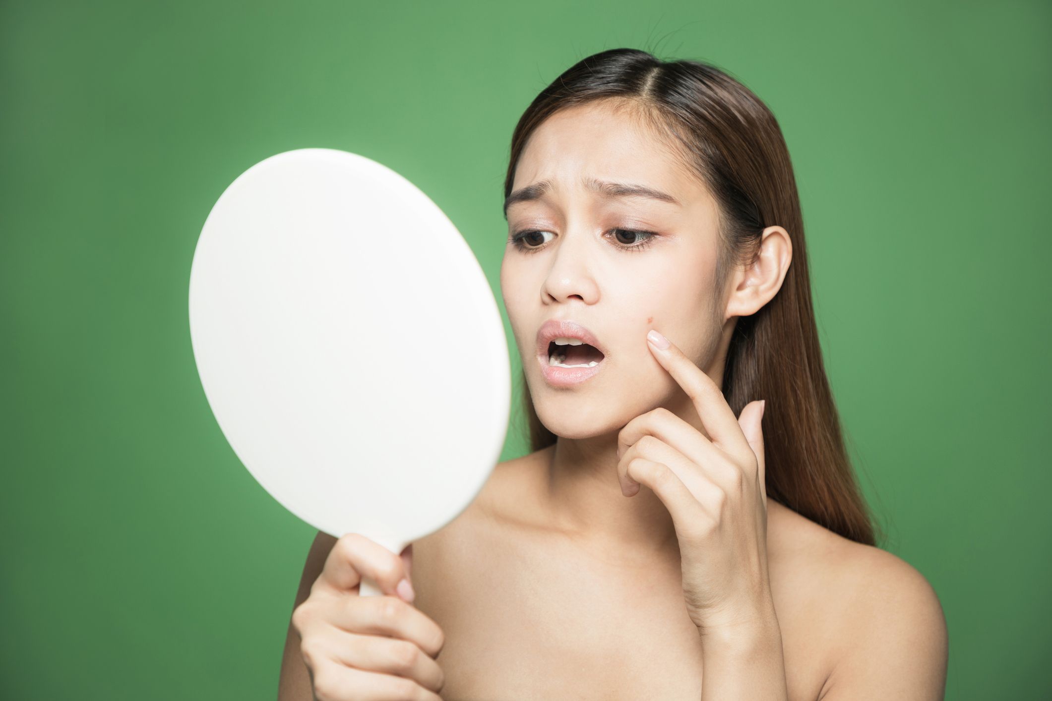 Young woman checking her skin. Skin care concept.