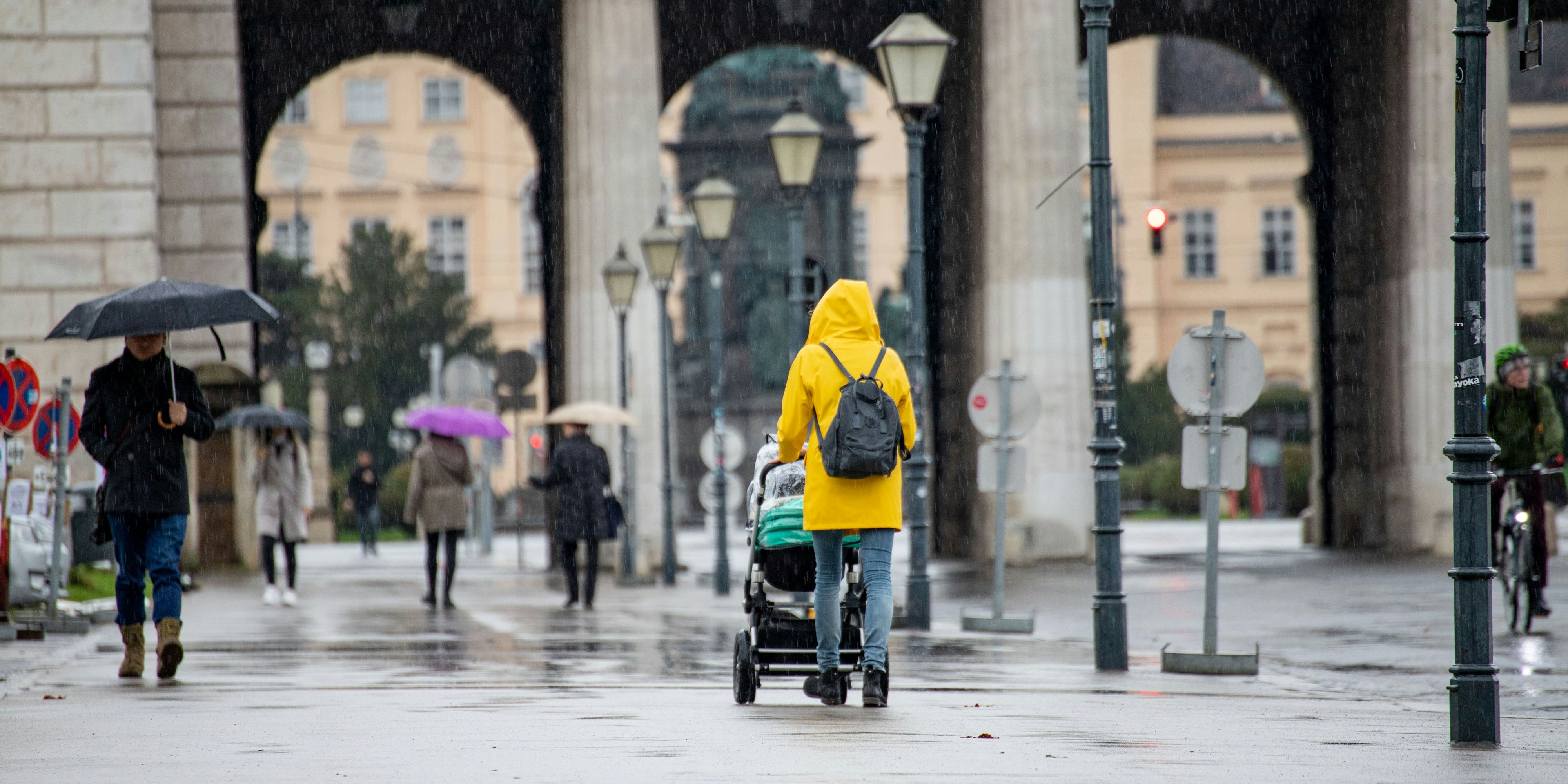 Download von www.picturedesk.com am 21.11.2020 (08:19).  Das Wetter zeigt sich kalt und regnerisch im Herbst in Wien . Im Bild: Frau in gelber Regenjacke spaziert mit einem Kinderwagen am Wiener Heldenplatz. Oktober 2020 // Autumn: Rainy and cold weather conditions in Vienna. Picture: Woman wears a yellow rain coat and pushes a stroller in Vienna, Austria. October 2020 - 20201030_PD13649 - Rechteinfo: Rights Managed (RM)
