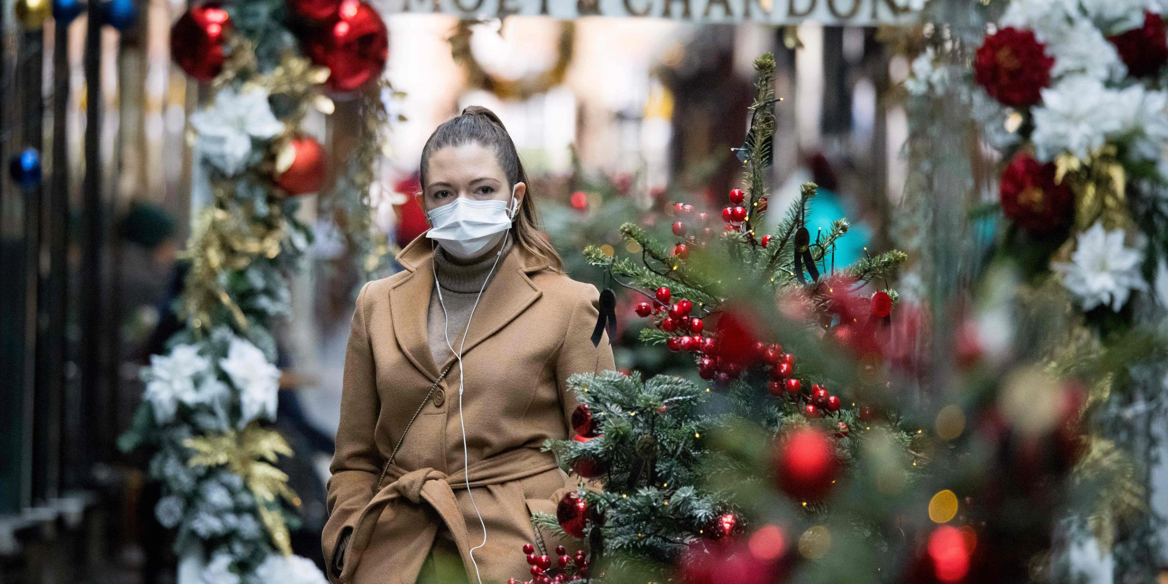 Eine Passantin mit Schutzmaske in einer Einkaufsstraße voller Weihnachtsdeko