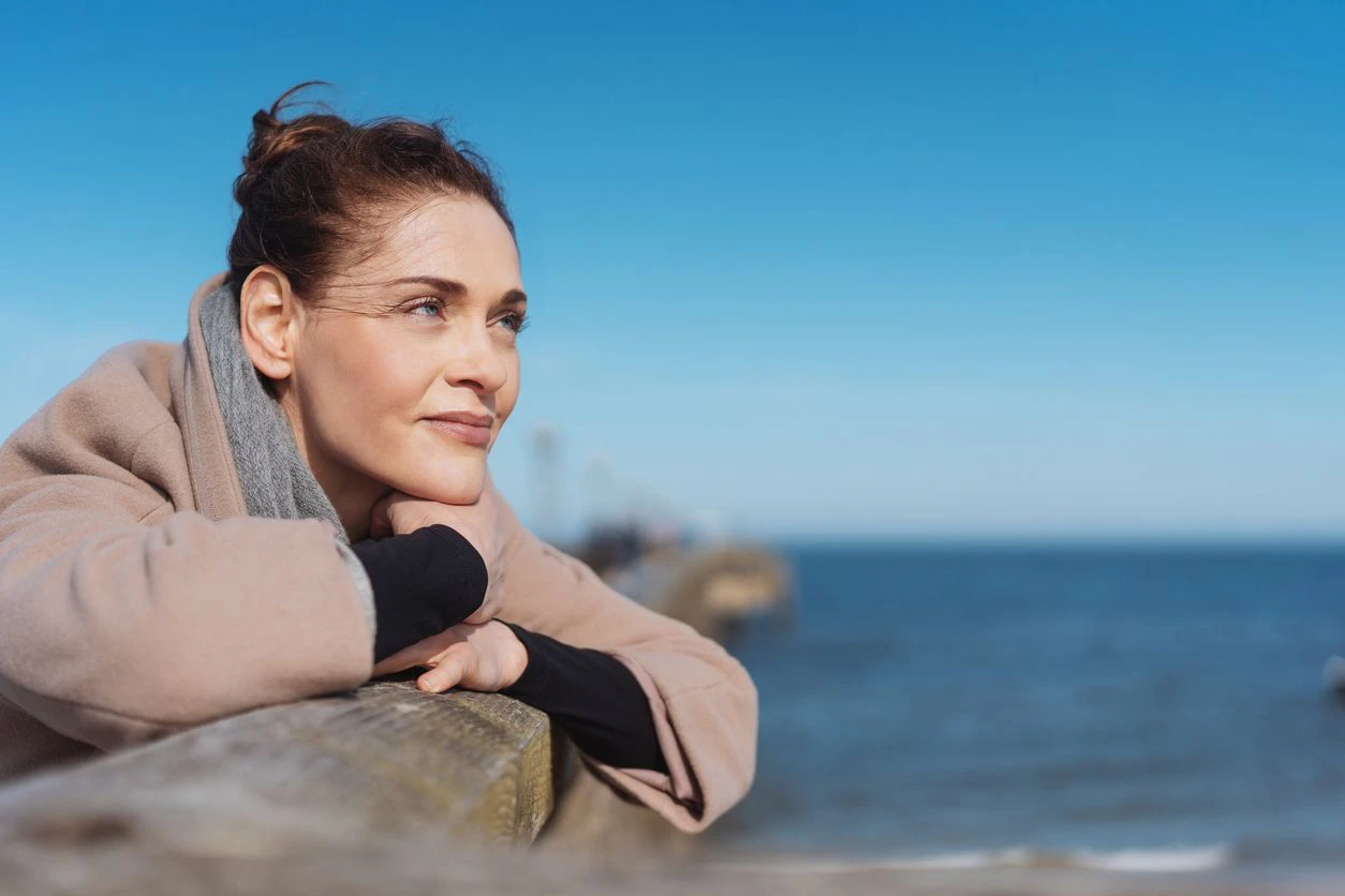 Eine Frau blickt nachdenklich über den Strand