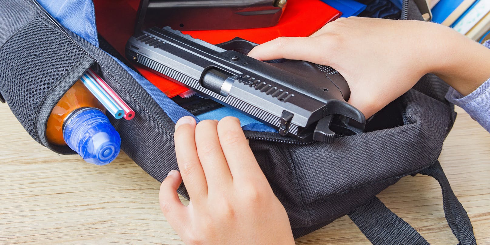Ein junger Schüler zieht eine Pistole aus seinem Rucksack. (Symbolbild)
