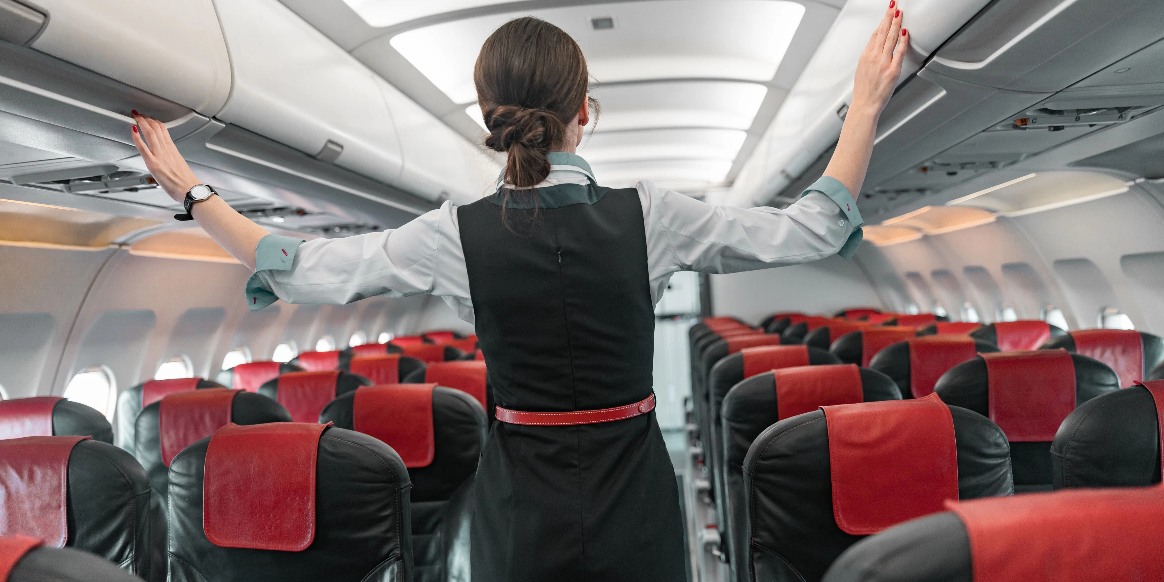 Female flight attendant doing her job in airplane stock photo. Airways concept