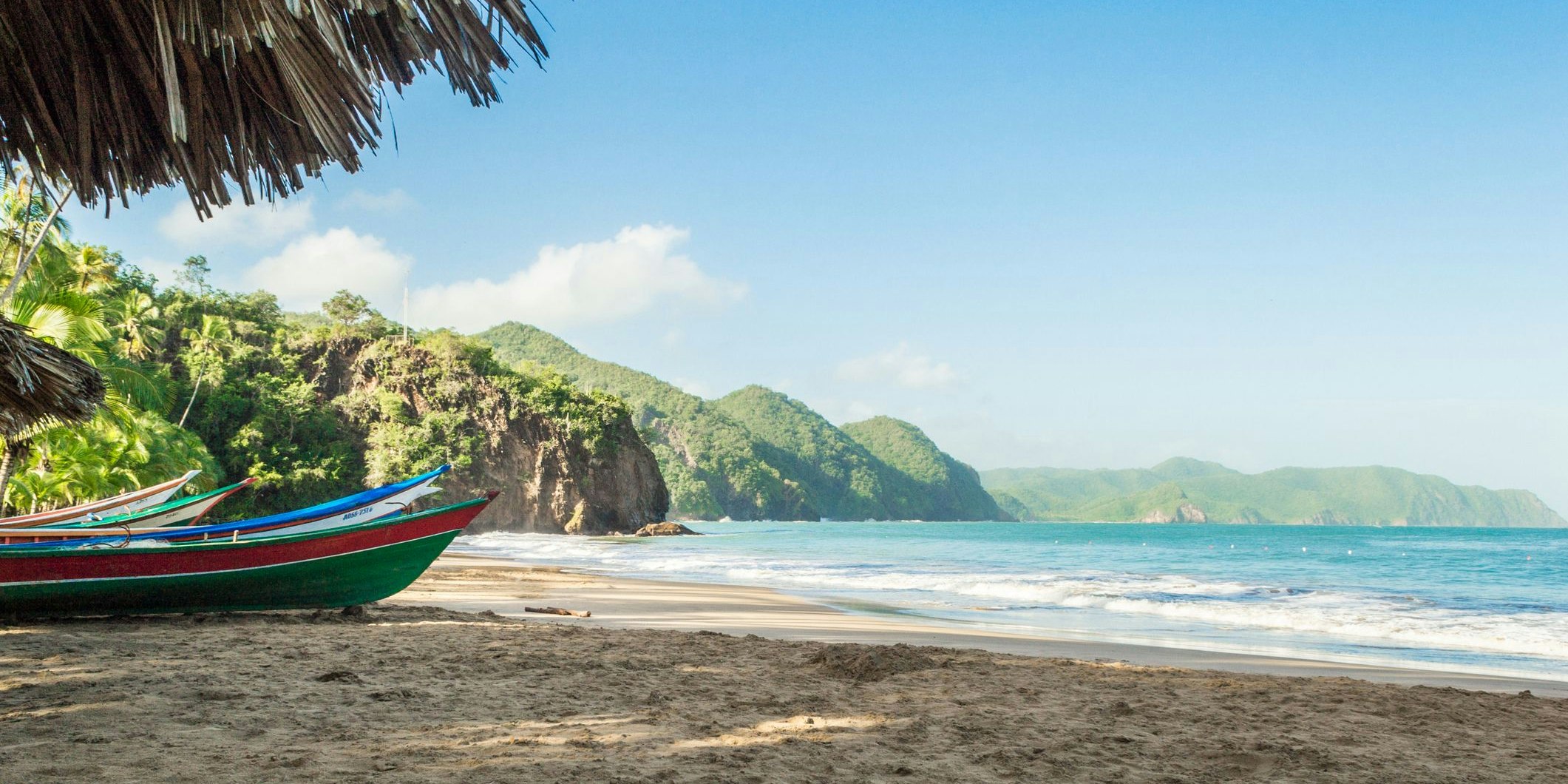 Caribbean beach landscape with the mountains in the background, small and colorful boats stranded in the sand. Medina Beach, Venezuela