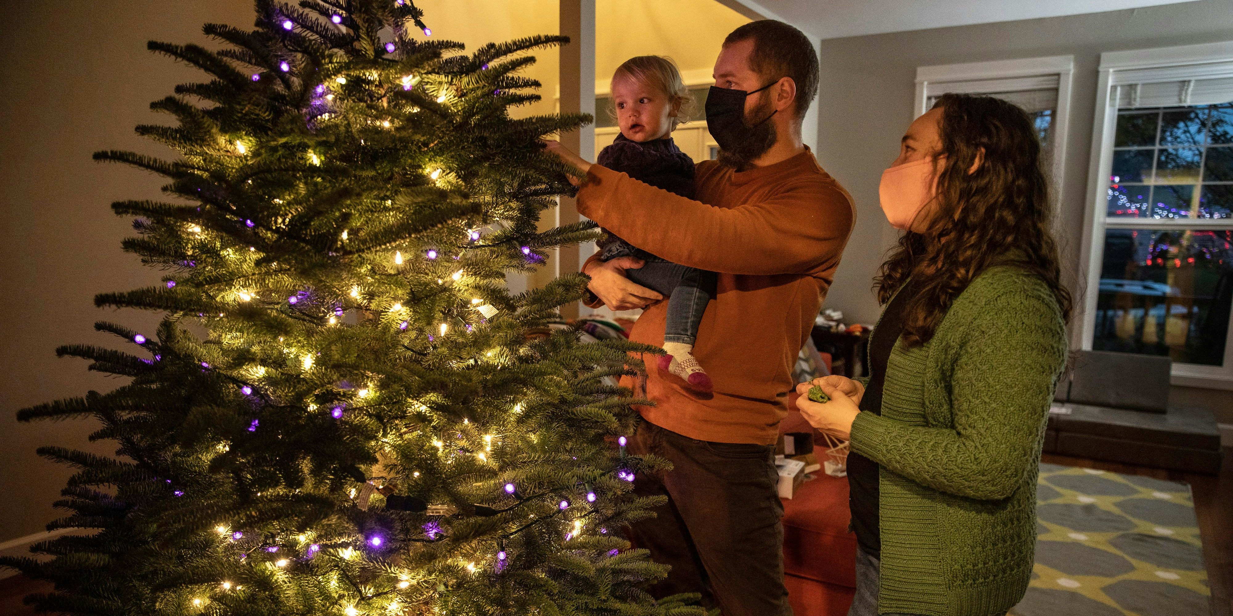 Download von www.picturedesk.com am 17.12.2020 (11:38).  Ani Sirois places lights and decorations on the family's Christmas tree with daughter Ida, 2, and husband, Chadwick, at their home on Tuesday, Nov. 24, 2020 in Portland, Ore. Sirois, a respiratory nurse, has spent months caring for coronavirus patients at a Portland hospital. But on a recent sunny day, COVID-19 seemed far away as she, her husband and their 2-year-old daughter roamed a Christmas tree farm in search of the perfect evergreen for a holiday season unlike any other. The family was tree-shopping nearly a week before Thanksgiving and, for the first time, they were picking their own tree instead of buying a pre-cut one. (AP Photo/Paula Bronstein) - 20201123_PD8184 - Rechteinfo: Rights Managed (RM)