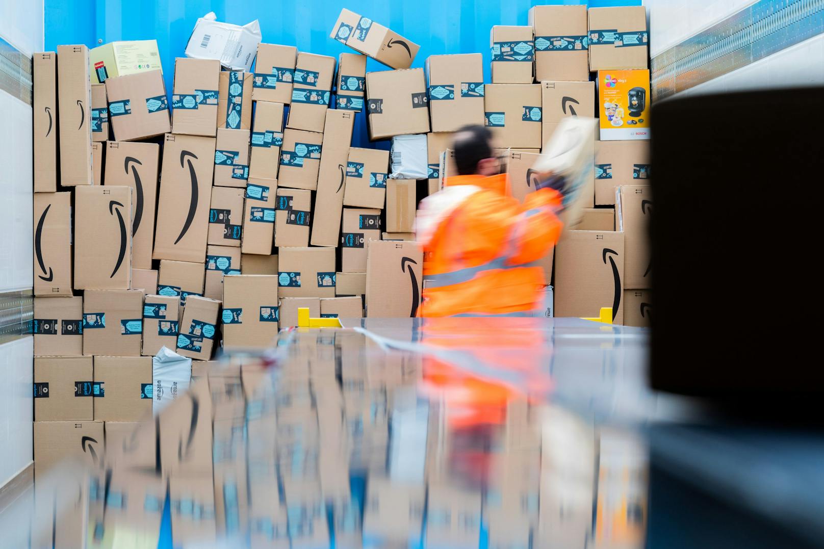 Ein Mitarbeiter verlädt Amazon-Packerl in einem Lkw. Amazon gab mögliche Lieferverzögerungen bekannt.