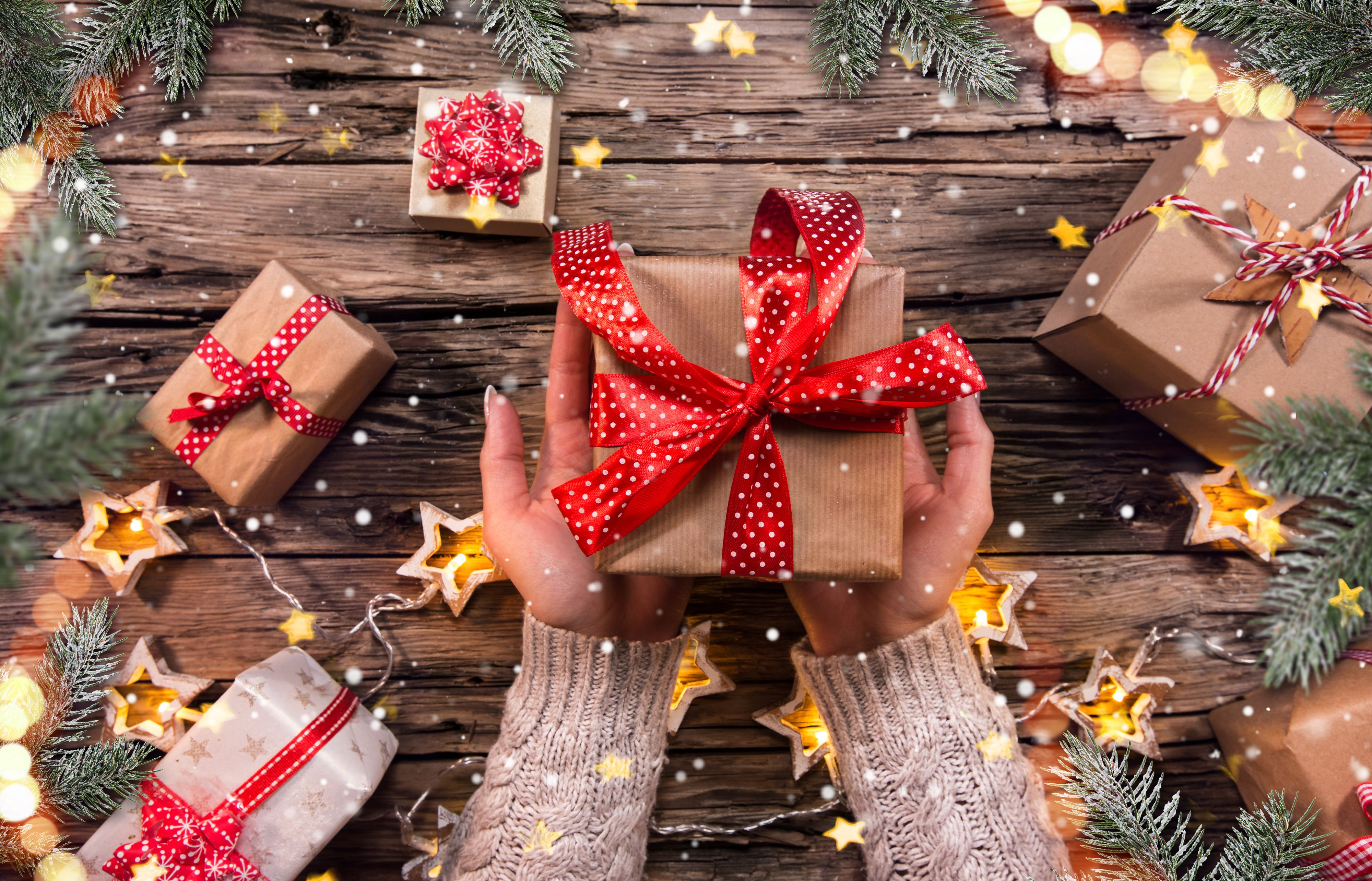Top view of woman hands with gift box on wooden table.