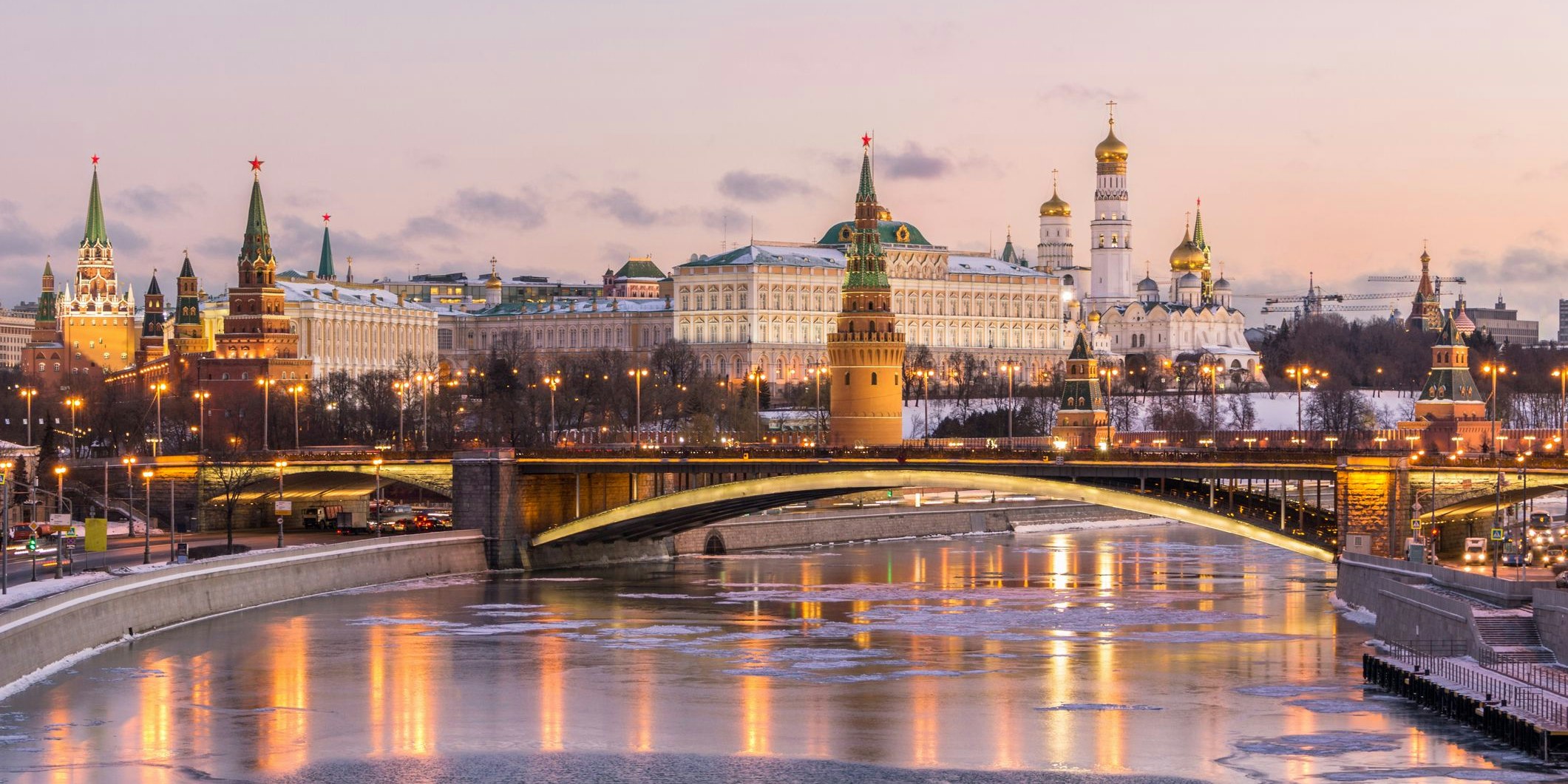 Illuminated Moscow Kremlin and Moscow river in winter morning. Pinkish and golden sky with clouds. Russia