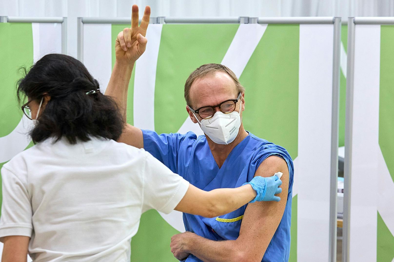 Christoph Wenisch, der Leiter der Infektionsabteilung hat seine erste Impfung erhalten und streckt die Finger aus zum Victory-Zeichen hoch.