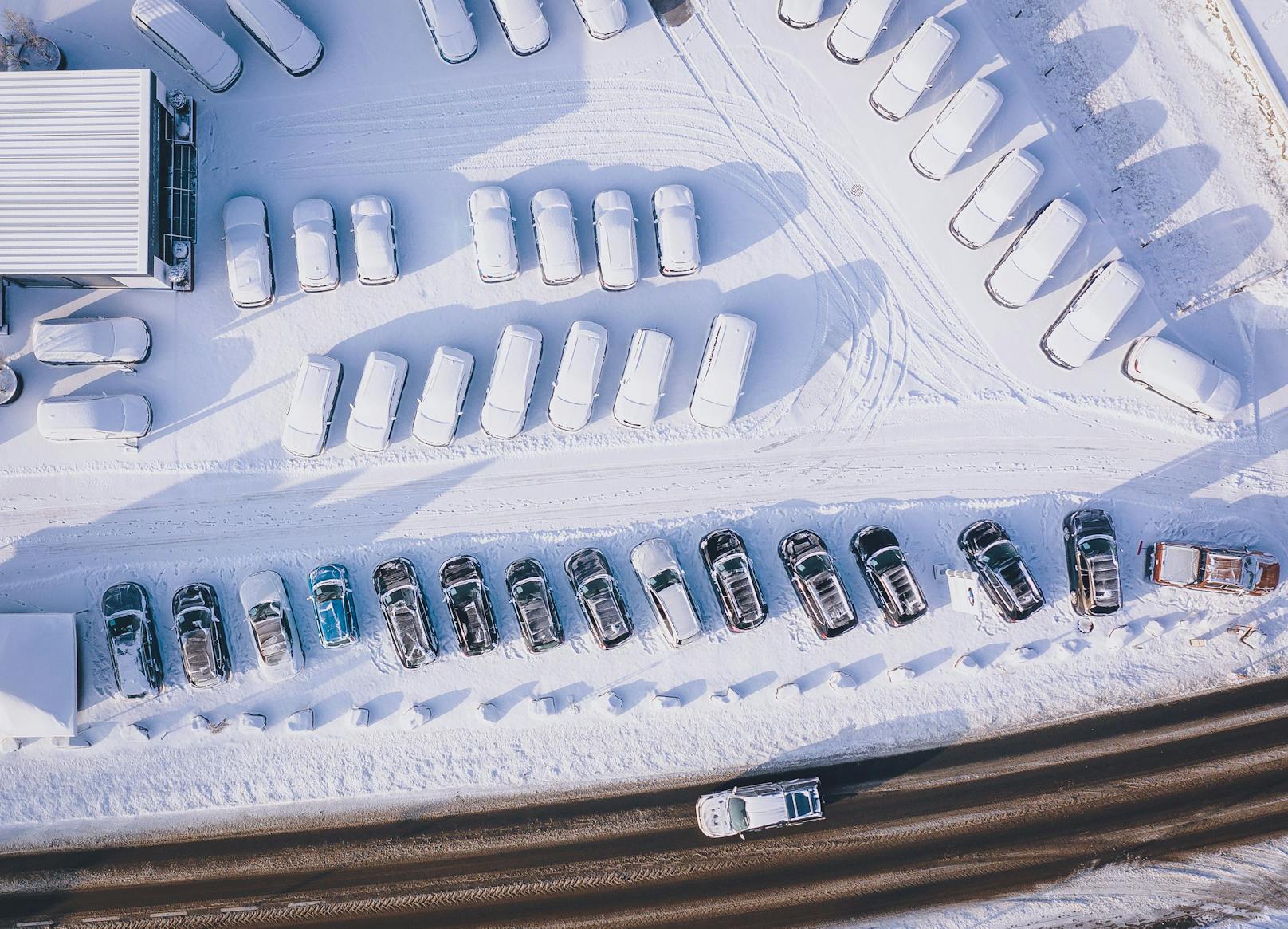 Fahrzeuge eines Autohändlers mit Neuschnee bedeckt auf einem Verkaufsplatz in Kaprun.