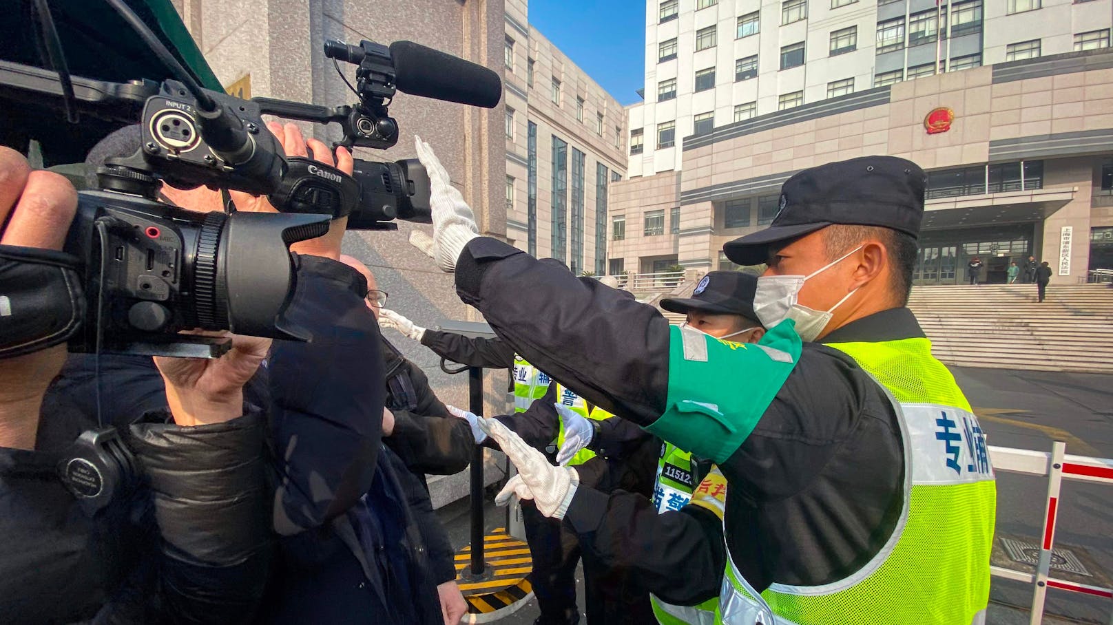 Ein Polizist deckt eine Kamera ab, um Journalisten an der Aufnahme von Filmmaterial vor dem Gericht zu hindern, wo Zhang Zhan vor Gericht steht. 