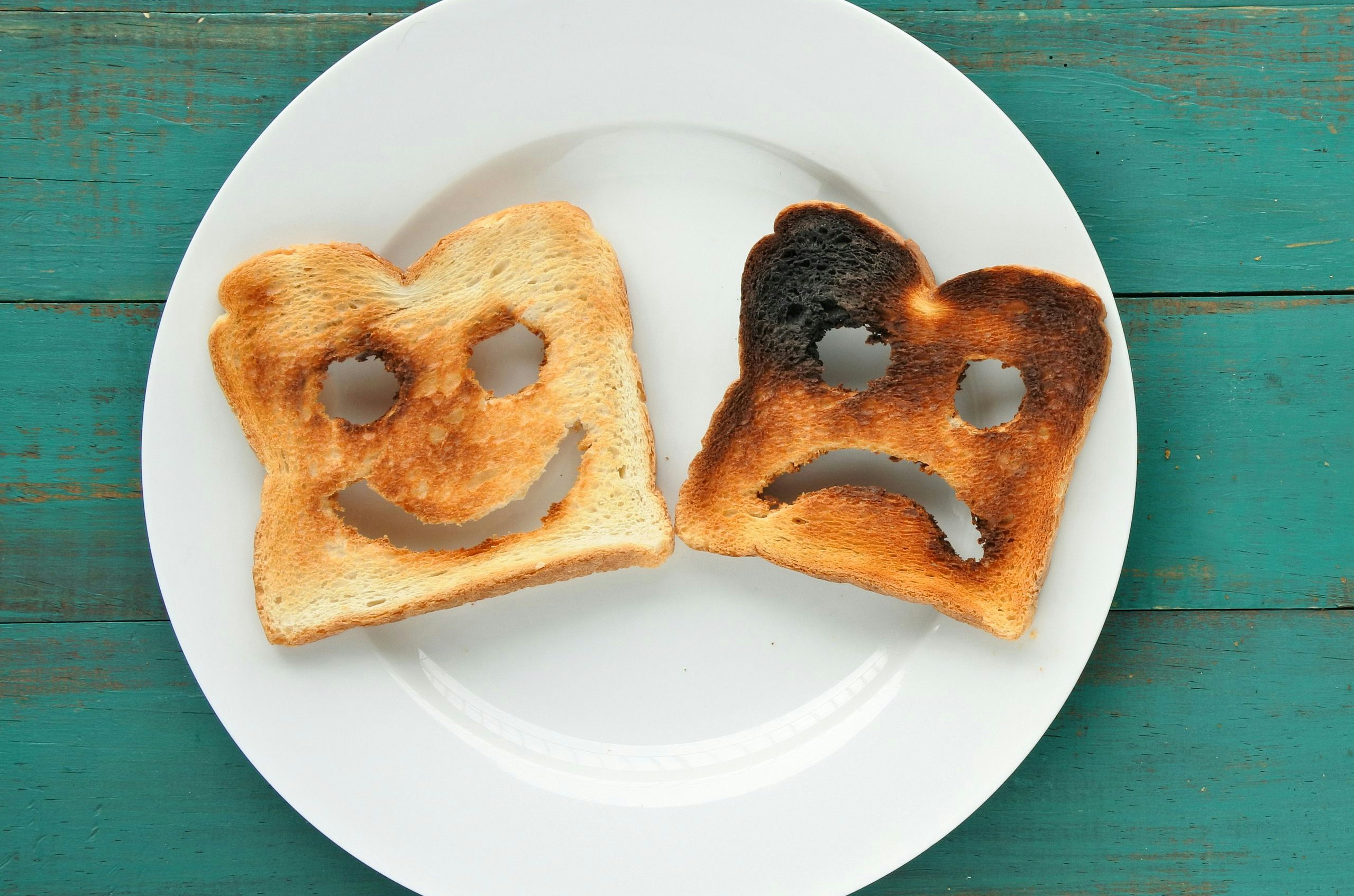 Flat lay view of two slices of toasted bread in a white plate. One is burned and one is well done. Relationship lifestyle concept. copy space