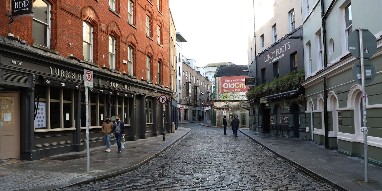 Fußgänger spazieren vor geschlossenen Geschäften in Dublin. 
