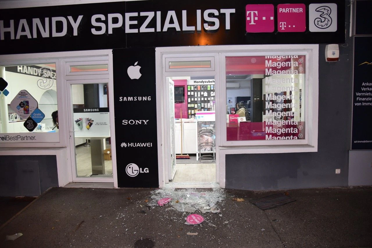 Unbekannte Täter traten die Glastüre des Handyshops ein.