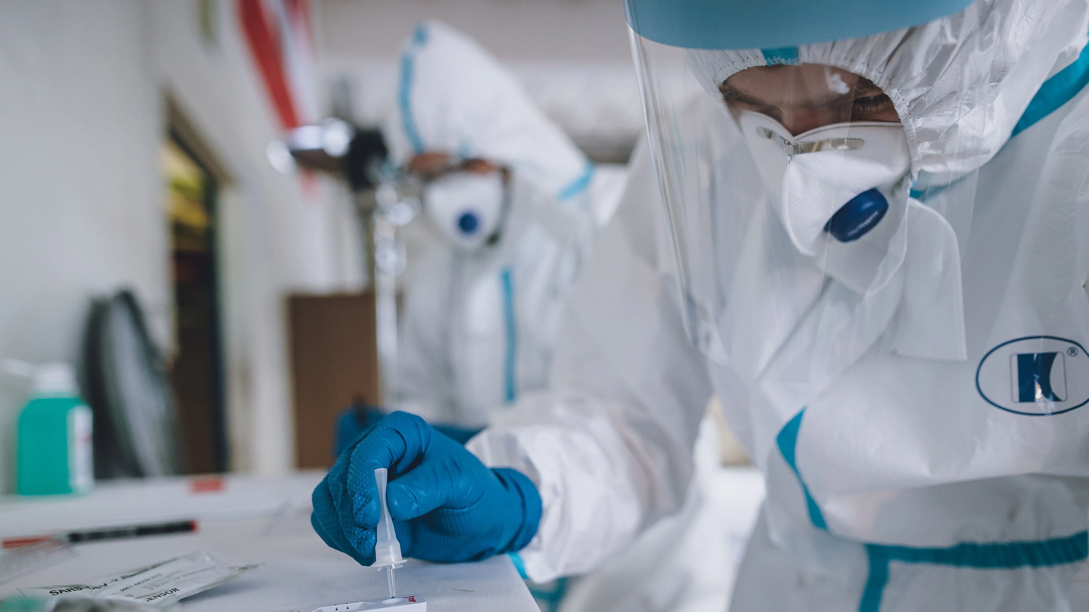Sanitätspersonal mit Schutzkleidung bei der Auswertung der Schnelltests während einer Massentestreihe 