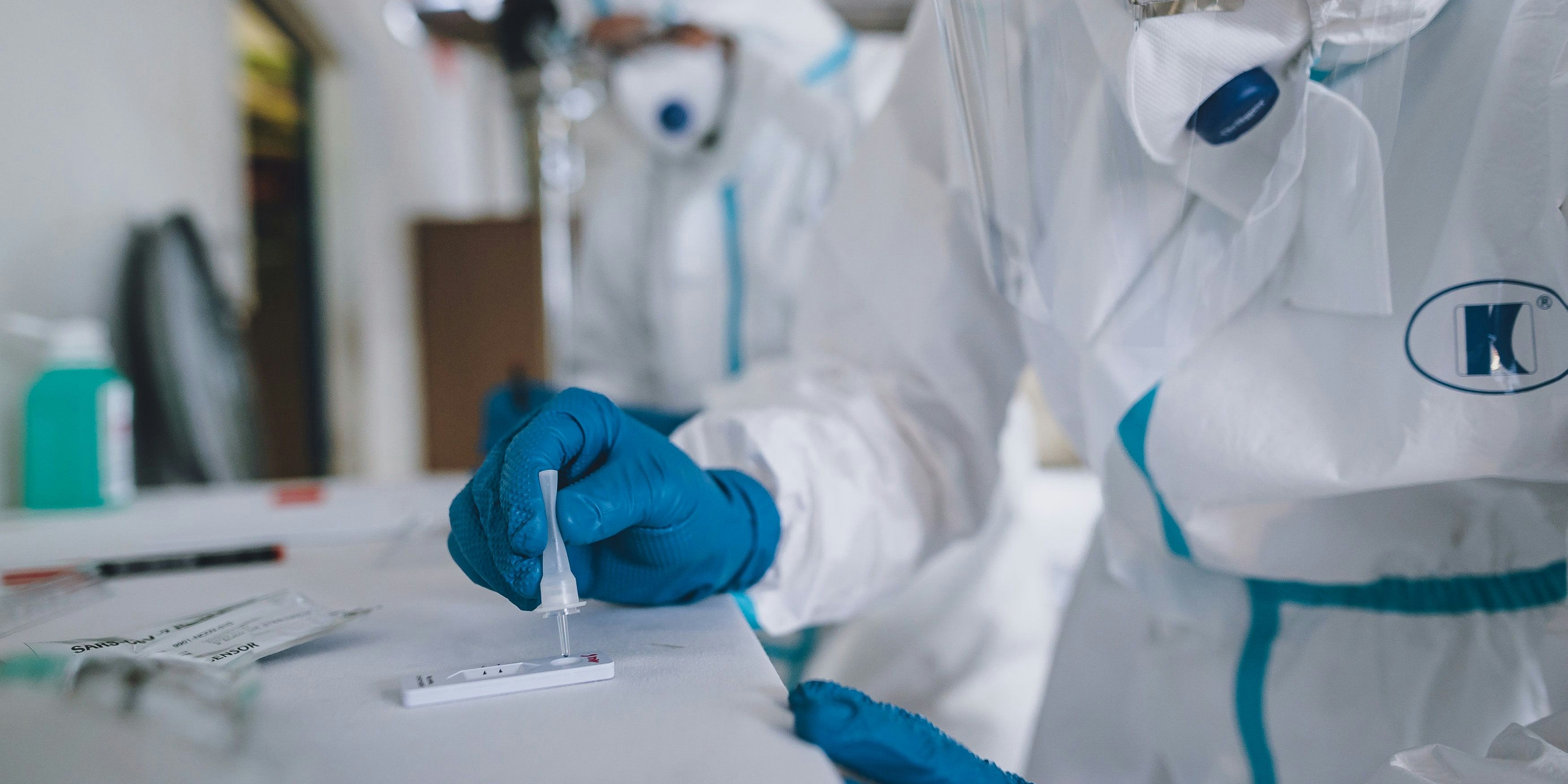 Sanitätspersonal mit Schutzkleidung bei der Auswertung der Schnelltests während einer Massentestreihe 