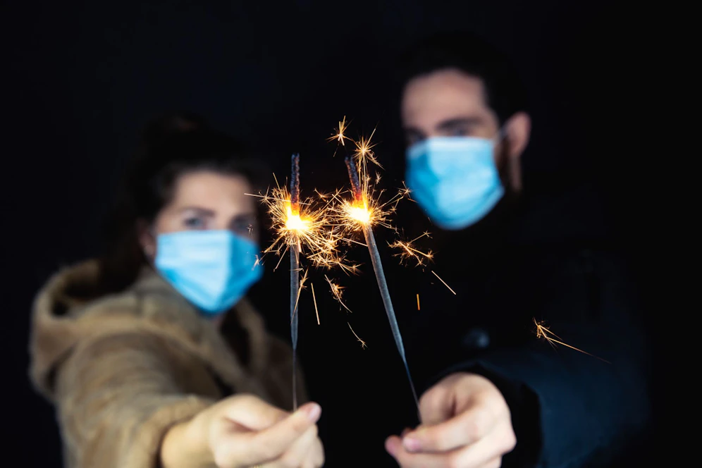 Sieht so Silvester 2020 aus? Ein junges Paar mit Gesichtsmasken und Wunderkerzen