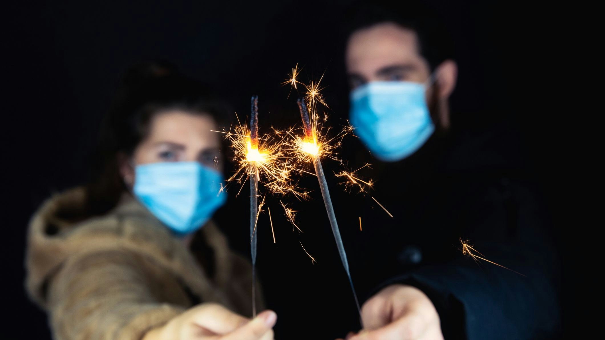 Sieht so Silvester 2020 aus? Ein junges Paar mit Gesichtsmasken und Wunderkerzen