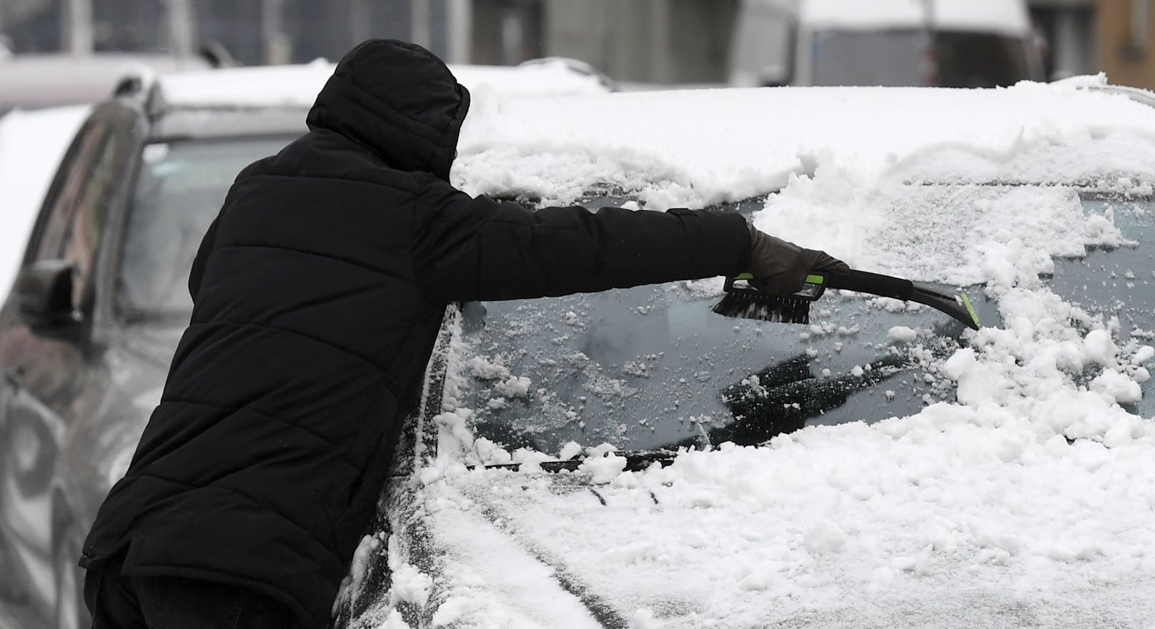 Ein Mann befreit am 3. Dezember 2020 sein Fahrzeug vom gefallenen Schnee in Wien.