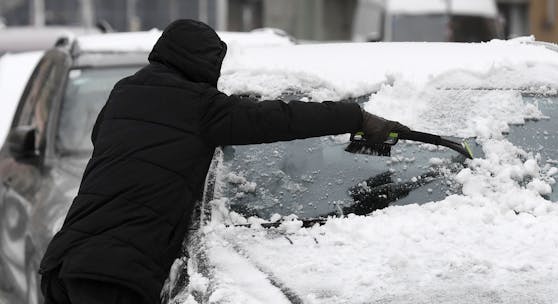 Ein Mann befreit am 3. Dezember 2020 sein Fahrzeug vom gefallenen Schnee in Wien.