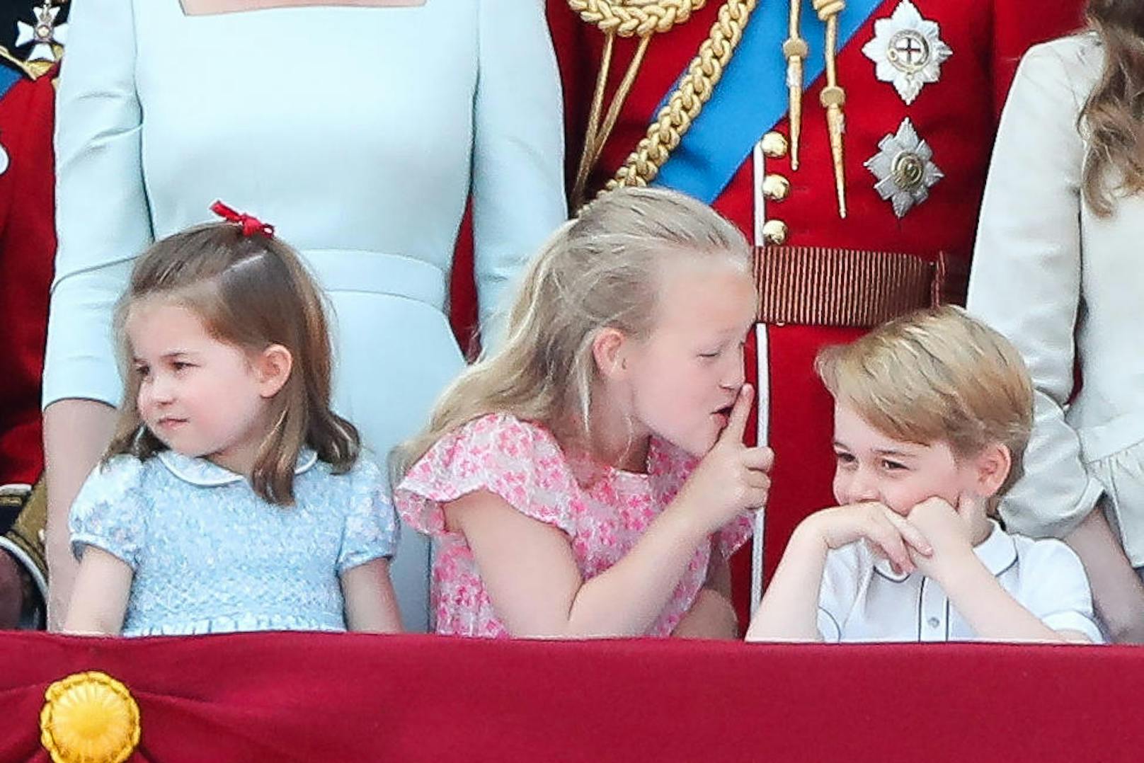 Und wieder mal blitzt Prinz George der Schalk aus den Augen. Diesmal ist es Savannah Phillips, die am königlichen Balkon dem royalen Verwandten den Mund verbietet. Die kleine Savannah ist ebenfalls blaublütig. Sie ist eine Urenkelin der Queen. Ihre Oma ist Anne, die Schwester von Prinz Charles.