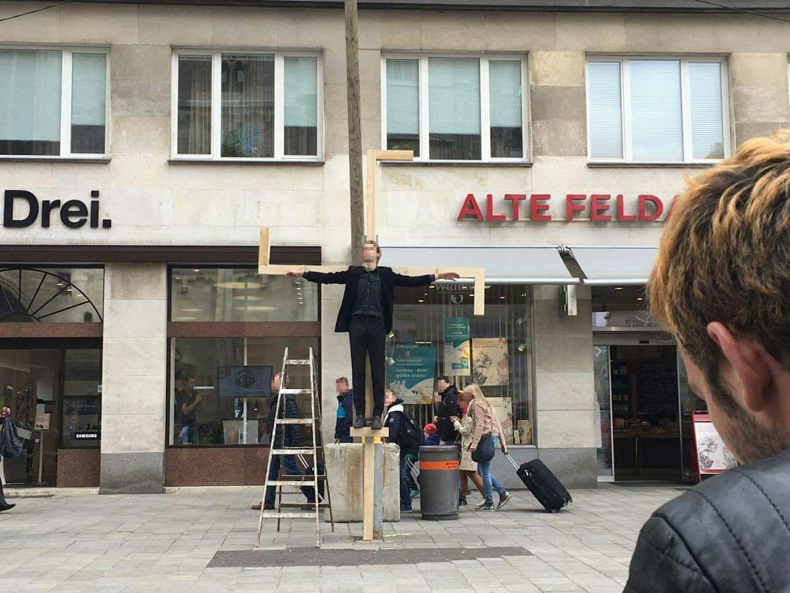 Ein Aktivist hing in Jesus-Pose an einem überdimensionalen Hakenkreuz am Stephansplatz