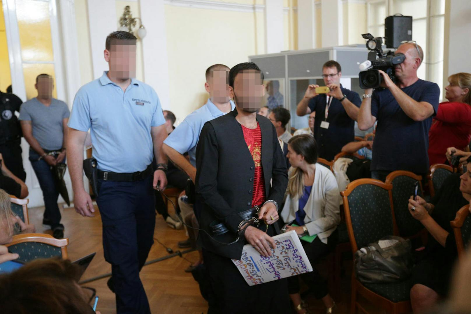 Unter schwerer Bewachung und in Handschellen sind am Mittwoch, 21. Juni 2017, zehn der elf Angeklagten im Schlepperprozess im Gericht in Kecskemet in Ungarn vorgeführt worden. Teils vermummte Justizwachebeamte begleiteten die Männer, die für den Erstickungstod von 71 Flüchtlingen verantwortlich sein sollen.