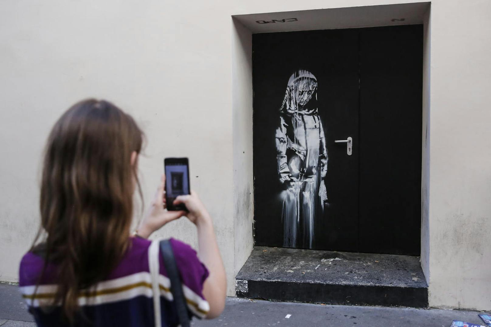 Gedenken an die Opfer des Terroranschlags: Ein Banksy Street Art Stencil an der Seitentür der Bataclan Musikhalle