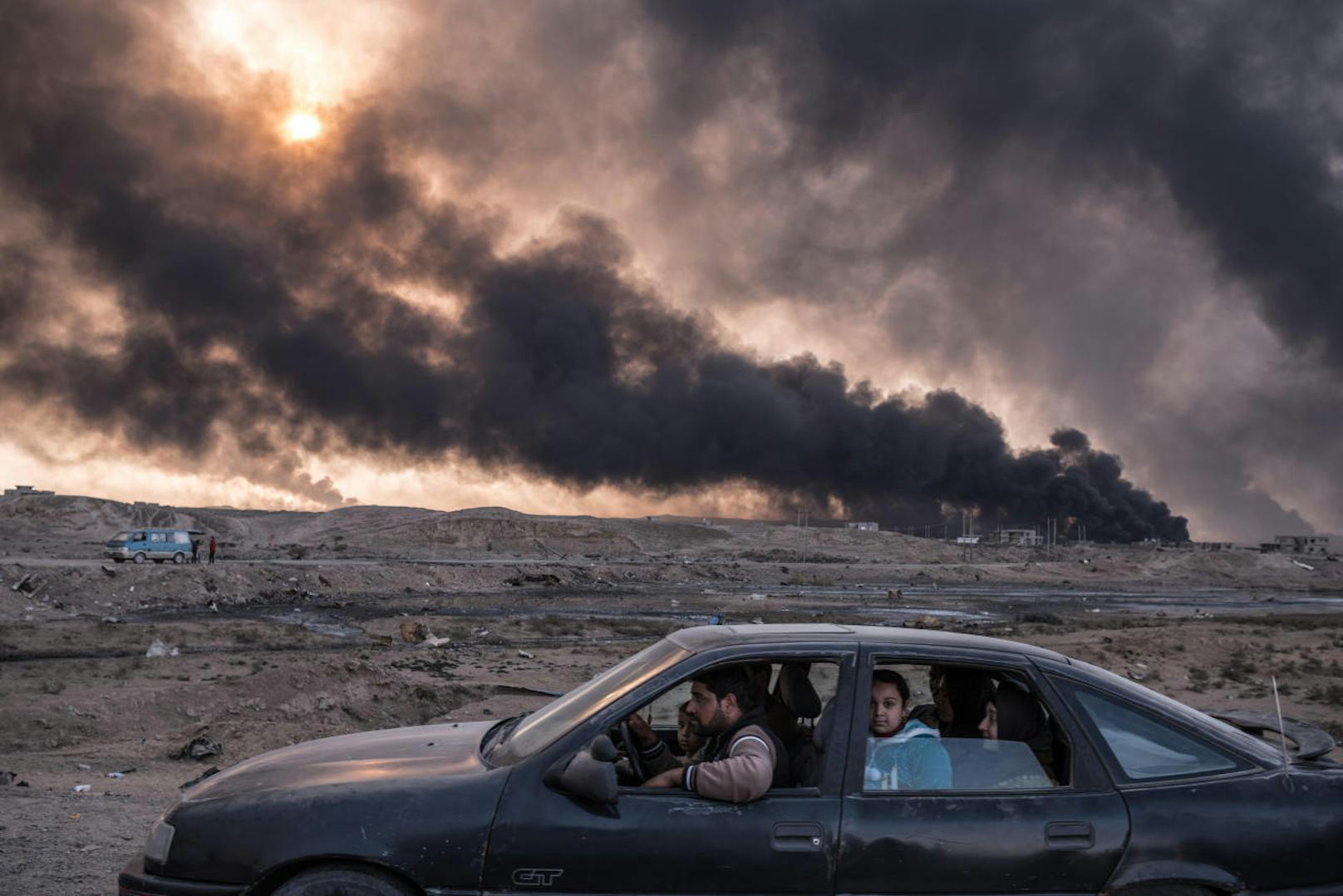 <b>Reportagen ? Zweiter Preis, Fotoserien</b>
Sergey Ponomarev, für The New York Times
Titel: Kampf um die Städte im Irak
Eine Familie auf der Flucht aus Mossul, im Hintergrund die brennenden Ölfelder von Qayyarah, 60 Kilometer südlich der Stadt, November 2016, Irak

