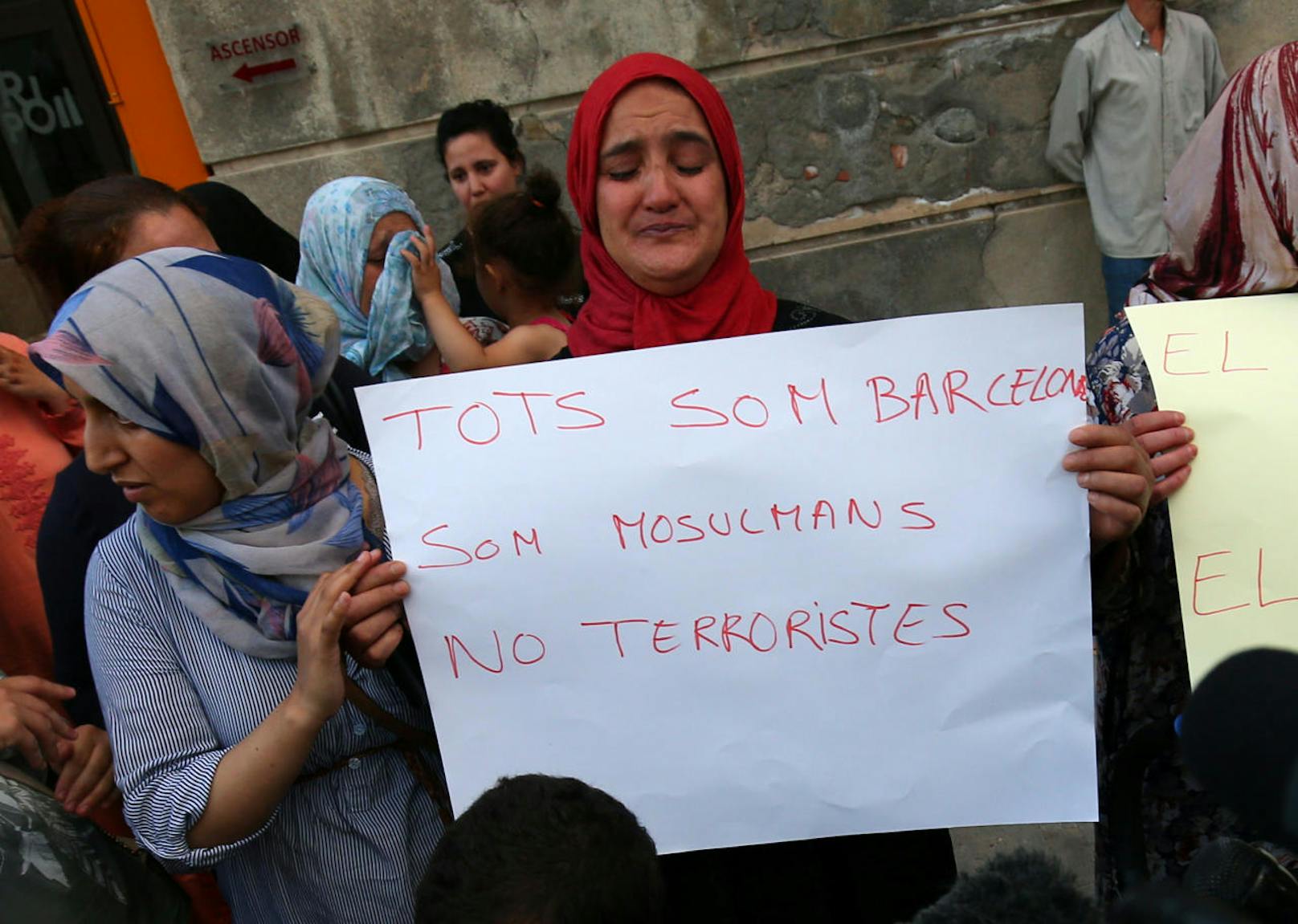 Die Mutter von Said Aalla, Youssef Aalla und Mohamed Aalla hält ein Schild gegen Terror neben Hafida Oukabir hoch.