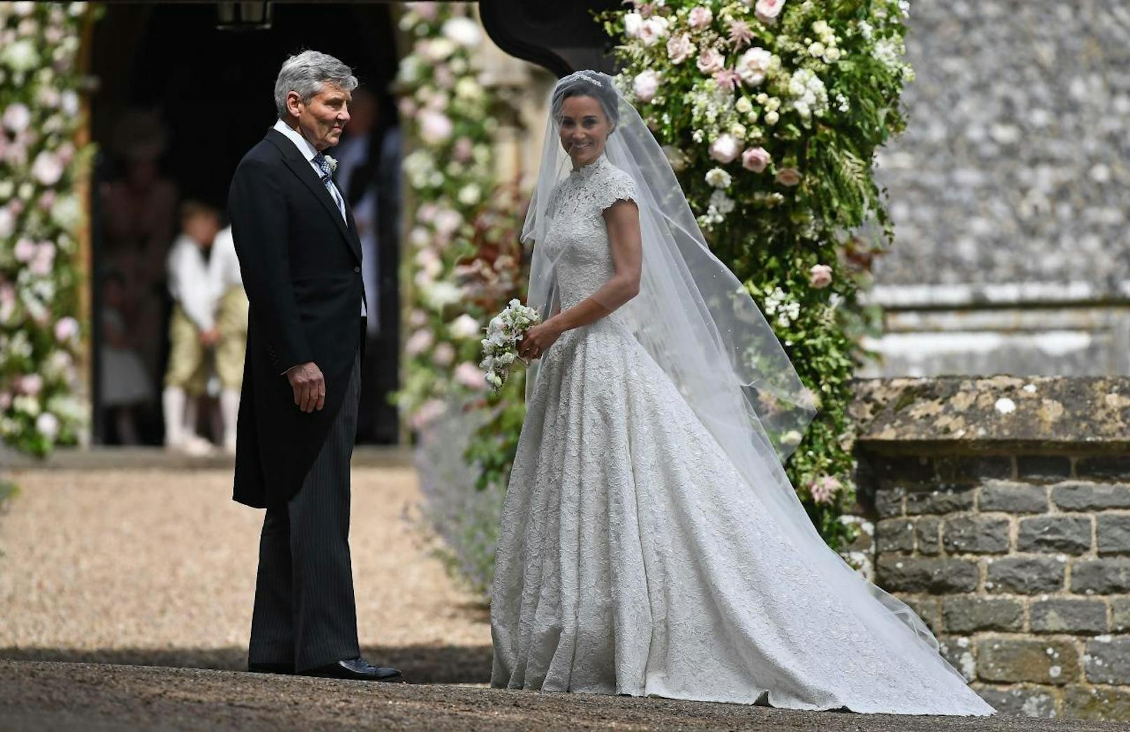 Pippa Middleton strahlt in einem wunderschönen weißen Hochzeitskleid aus Spitze. Ihr Vater Michael Middleton führt sie zum Altar.