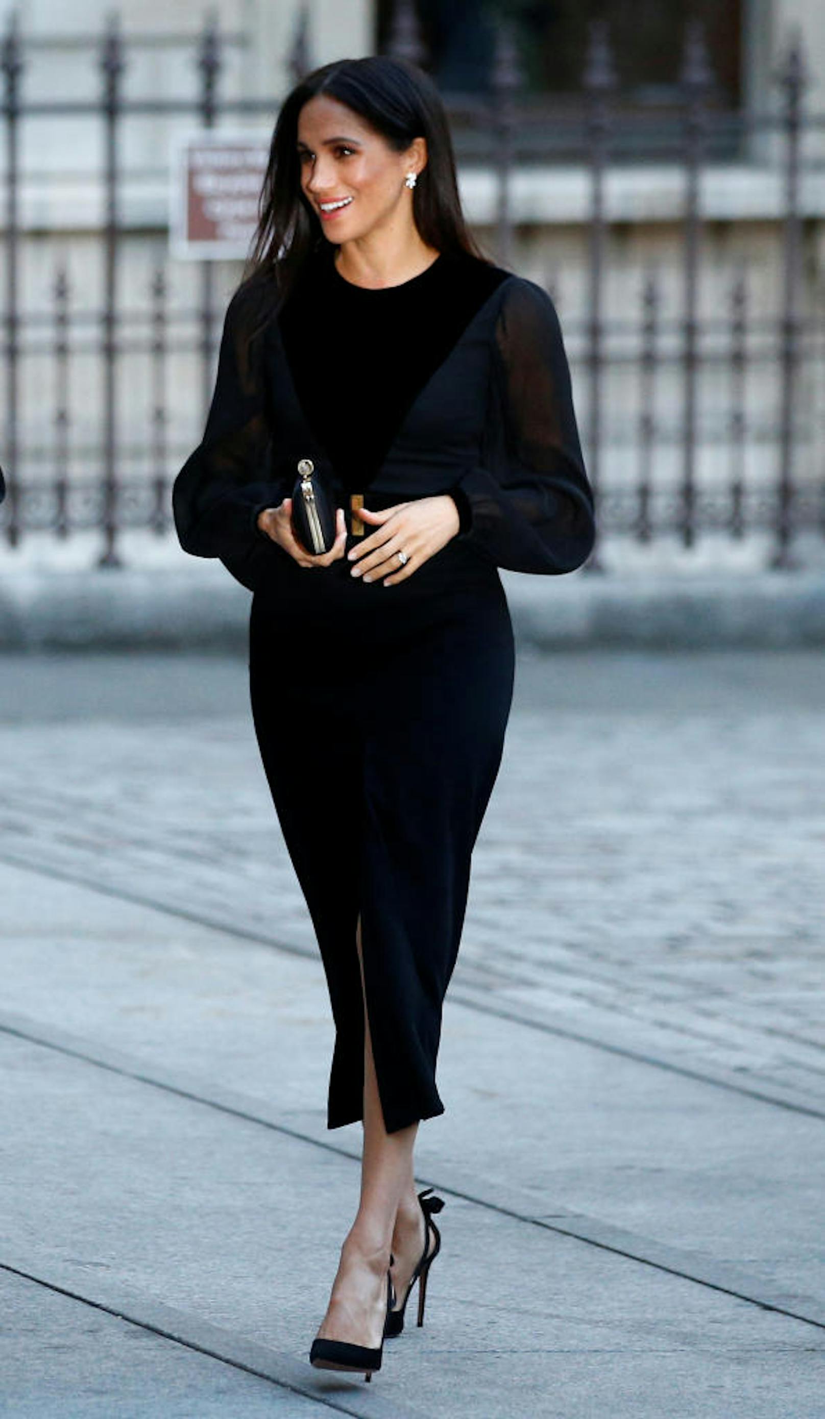 Meghan spazierte in subtiler Eleganz und sicheren Schrittes, gekleidet in einem langen, schwarzen Kleid ihres Hochzeitsdesigners Givenchy zur Ausstellungseröffnung.