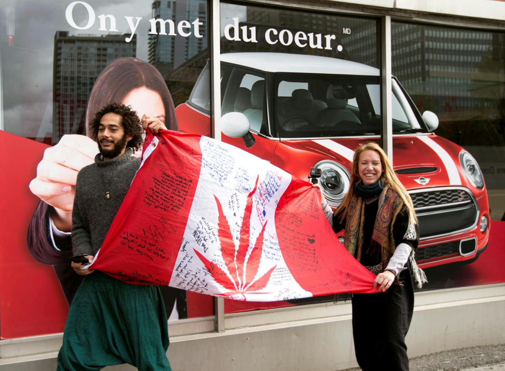 Ein Paar hält eine kanadische Flagge deren Ahornblatt durch ein Hanfblatt ersetzt wurde.