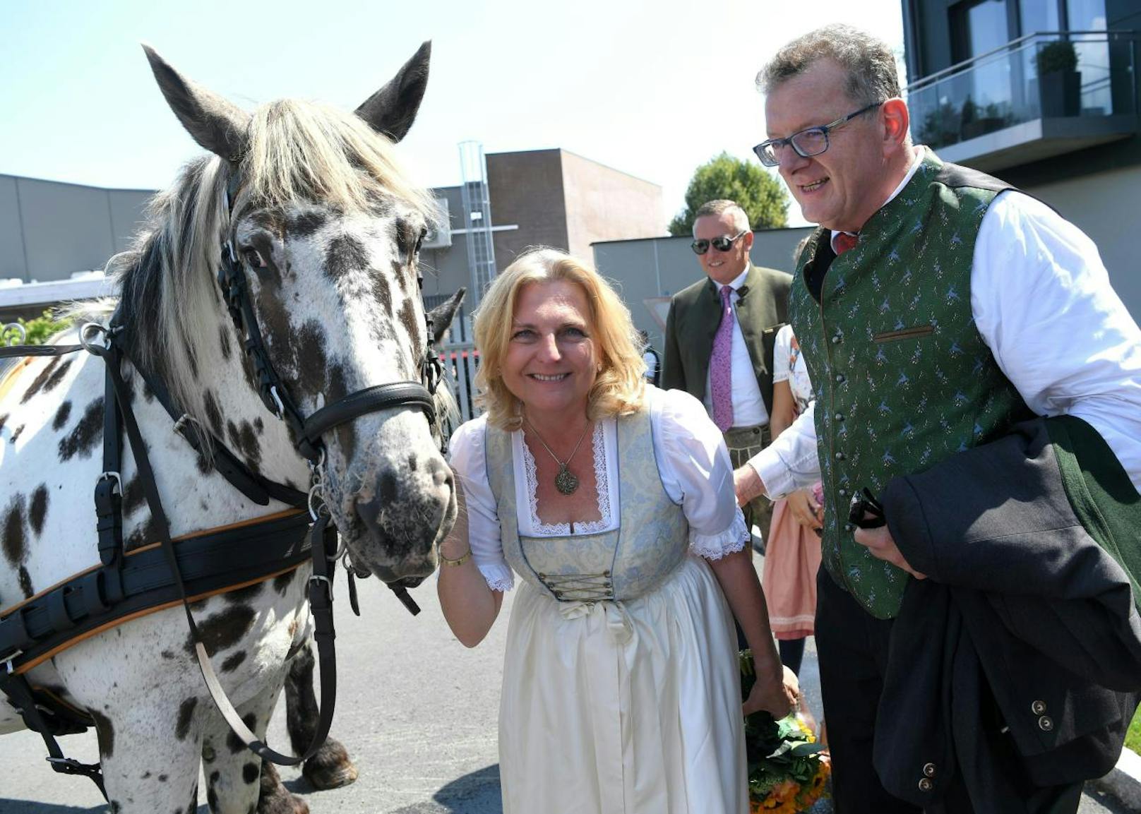 Kneissl und ihr Angetrauter Wolfgang Meilinger posieren mit Pferd.Im Hintergrund: Verteidigungsminister Mario Kunasek.
