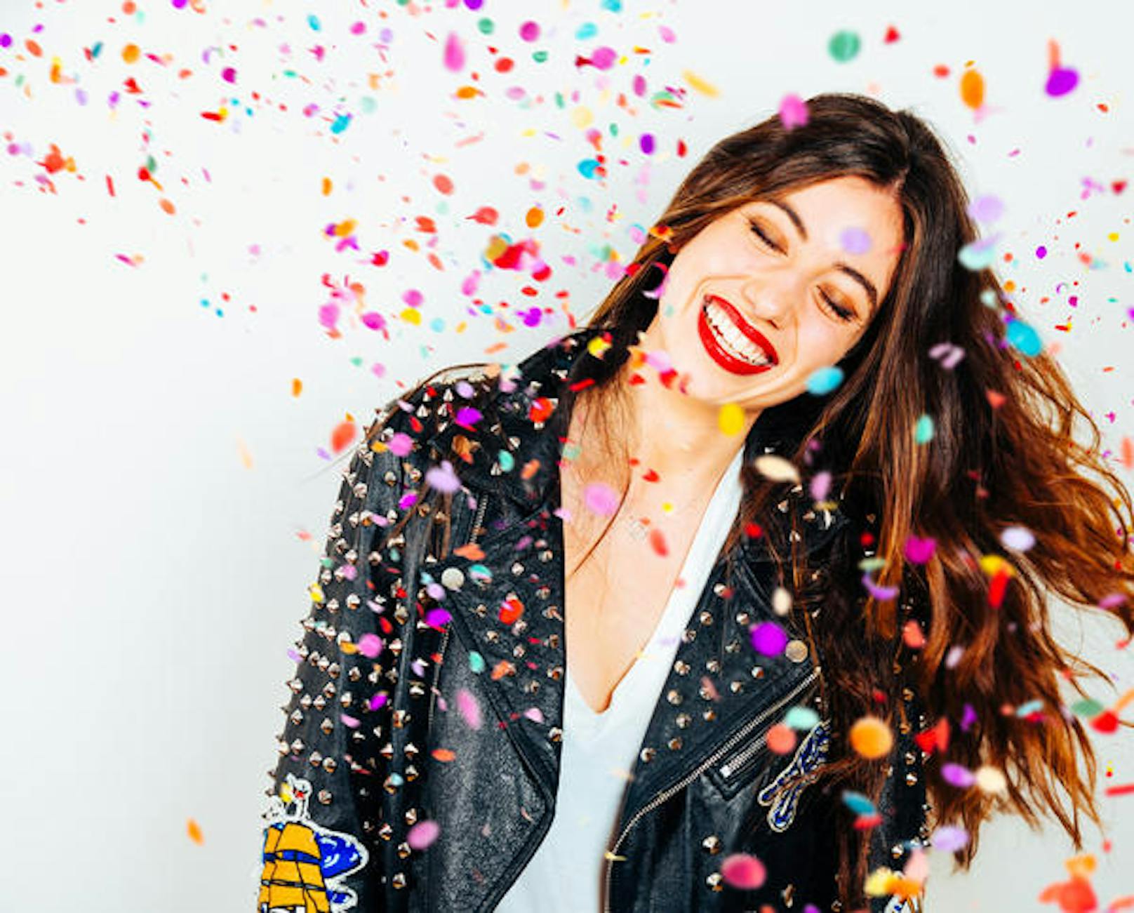 Happy young and beatiful woman with fashion leather jacket enjoying the party with confetti