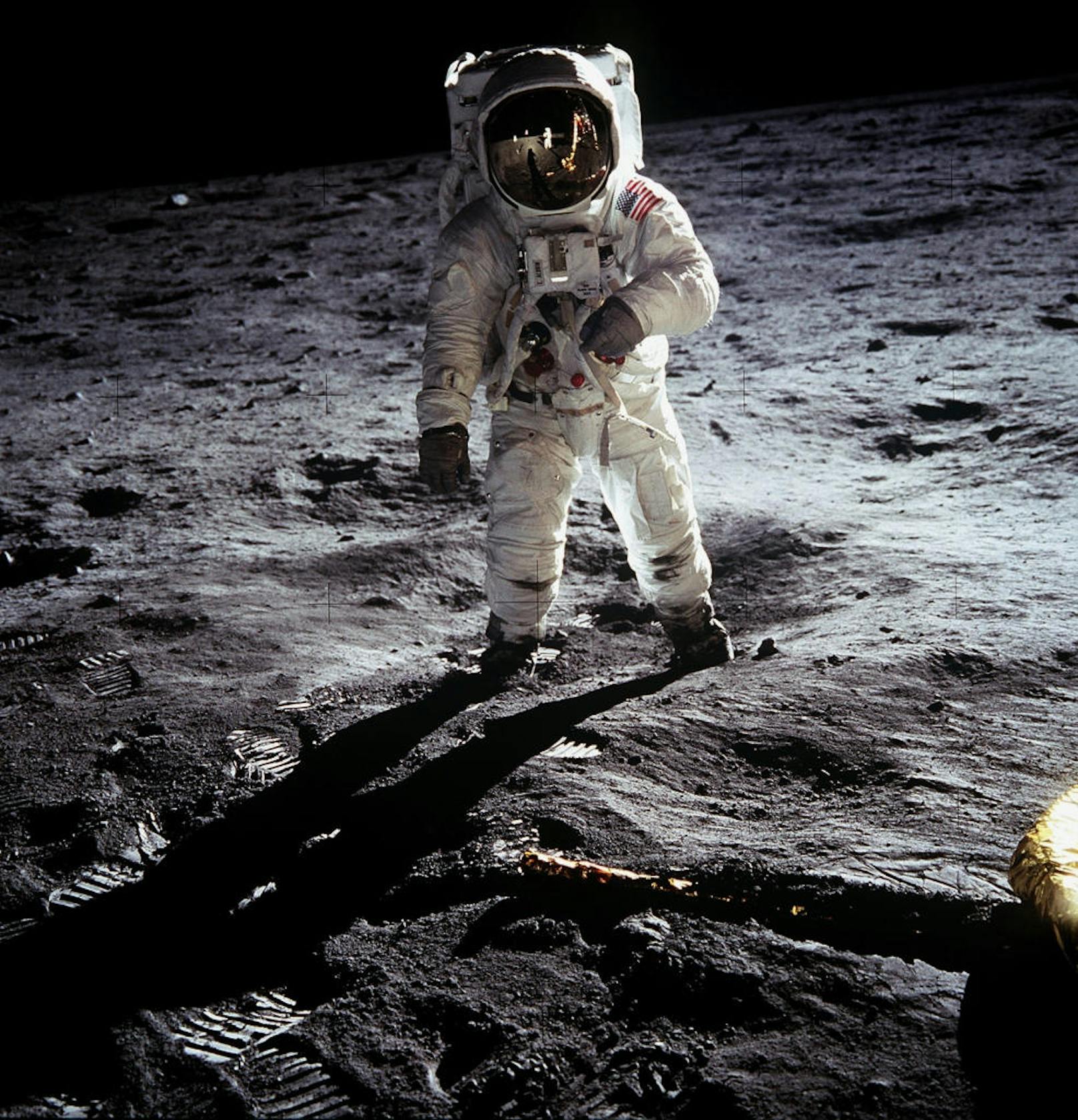 Buzz Aldrin auf der Mondoberfläche. In der Spiegelung seines Helmes sind sowohl die Mondfähre, als auch Neil Armstrong zu sehen. Ihr Kollege Michael Collins musste währenddessen das Kommandomodul im Orbit steuern. Er hat den Mond nie betreten.