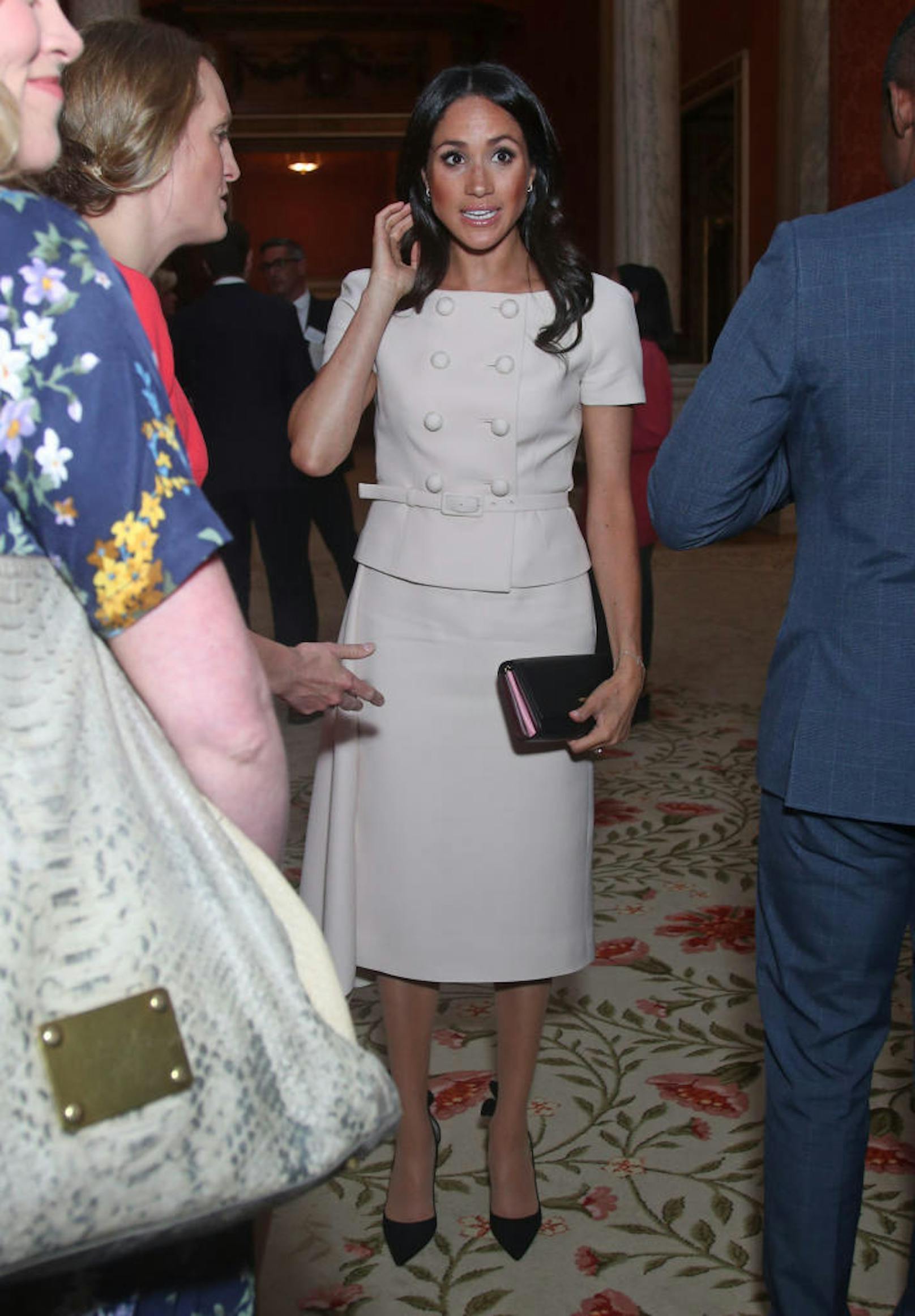 Die Frau von Prinz Harry in einem zartrosafarbenen Prada-Kleid und passender Tasche sowie schwarzen Aquazzura Deneuve Pumps.