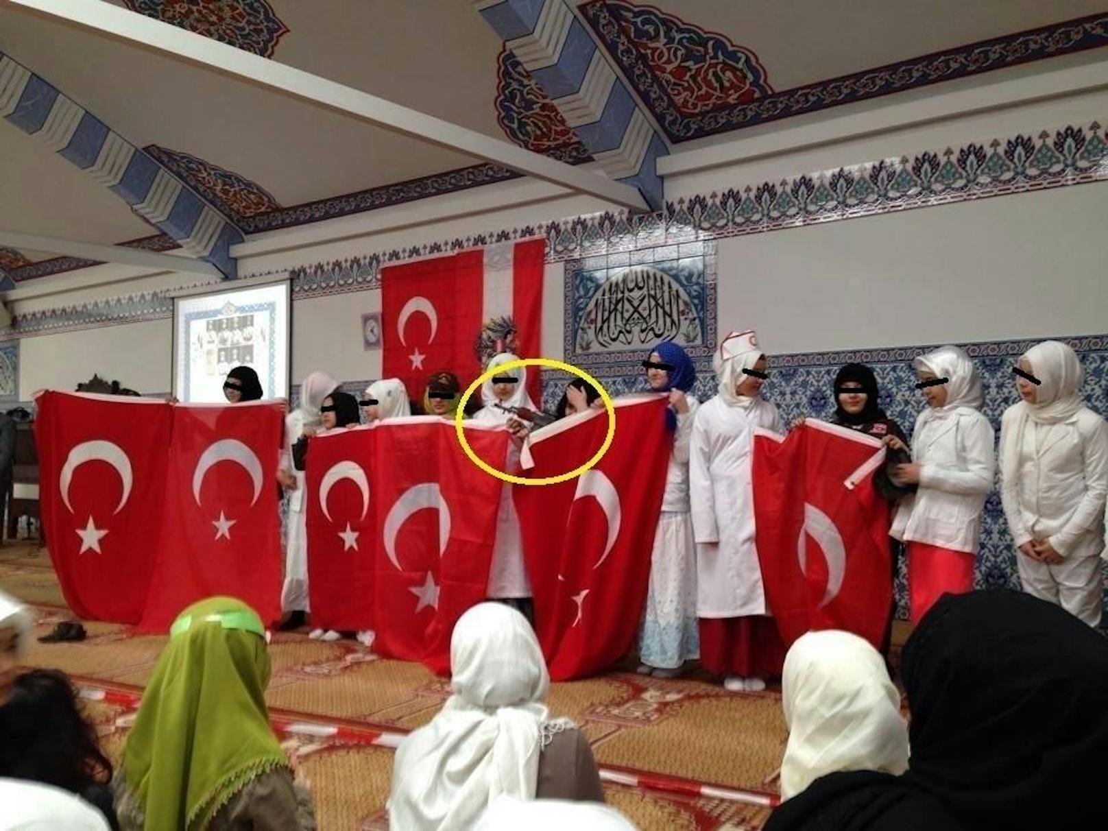 Ein Mädchen hält neben der türkischen Fahne eine Spielzeug-Kalaschnikow in der Hand.