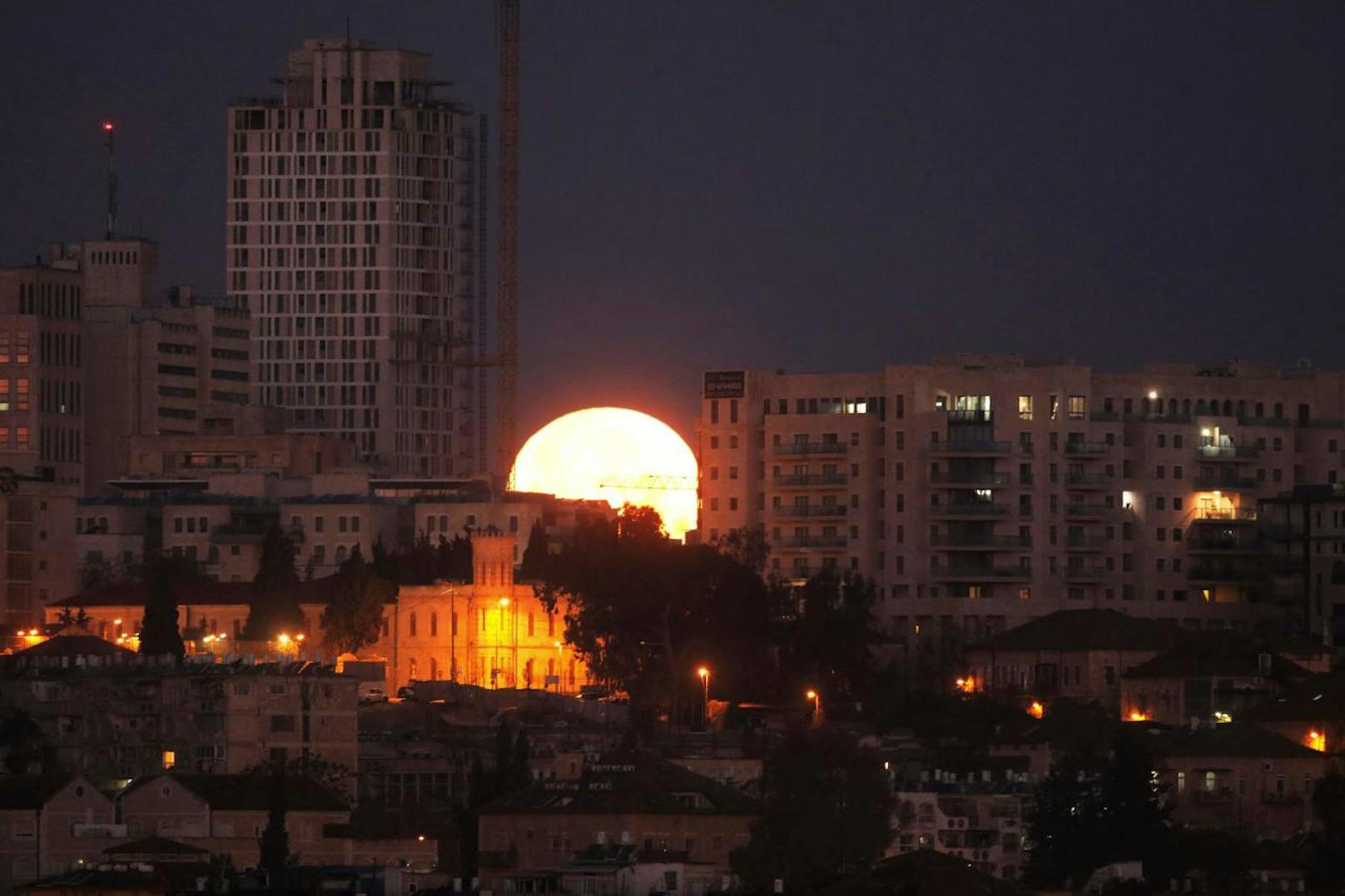 Nein, das ist nicht die aufgehende Sonne: Das ist der Mond, wie er heute vor der Skyline von Jerusalem unterging. Der seltene "Super-Blau-Blutmond" wird am Nachmittag in Teilen von Nordamerika, Asien, dem mitlleren Osten, Russland und Australien zu sehen sein.