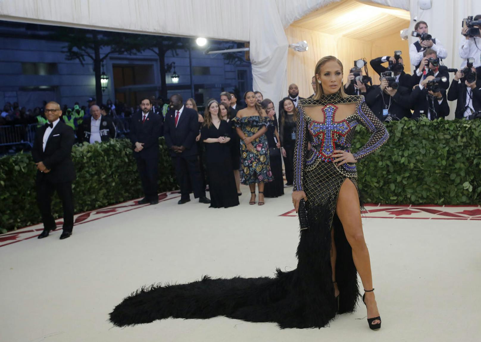 Jennifer Lopez posierte in einem gefiederten und verzierten Balmain-Kleid mit einem großen Kreuz in der Mitte, das an Buntglas erinnerte.